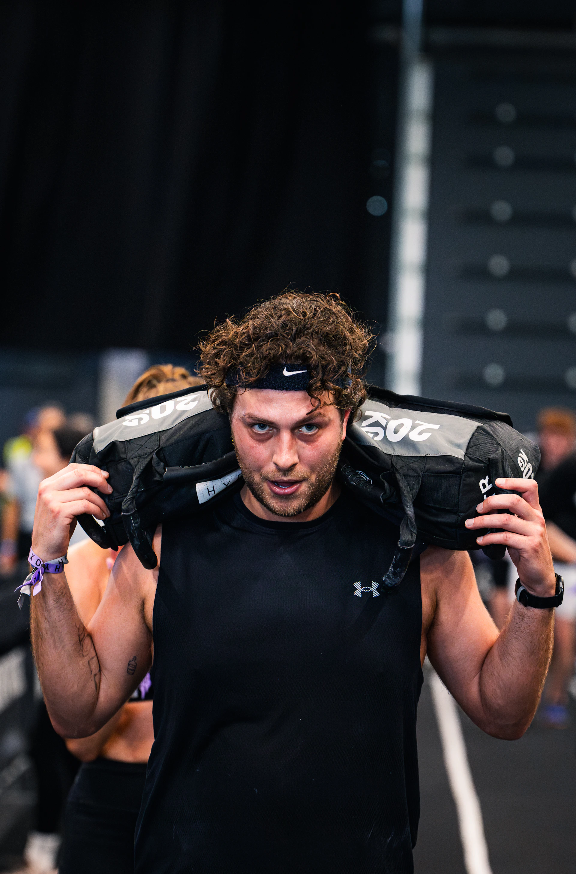 HYROX training athlete carrying sandbag
