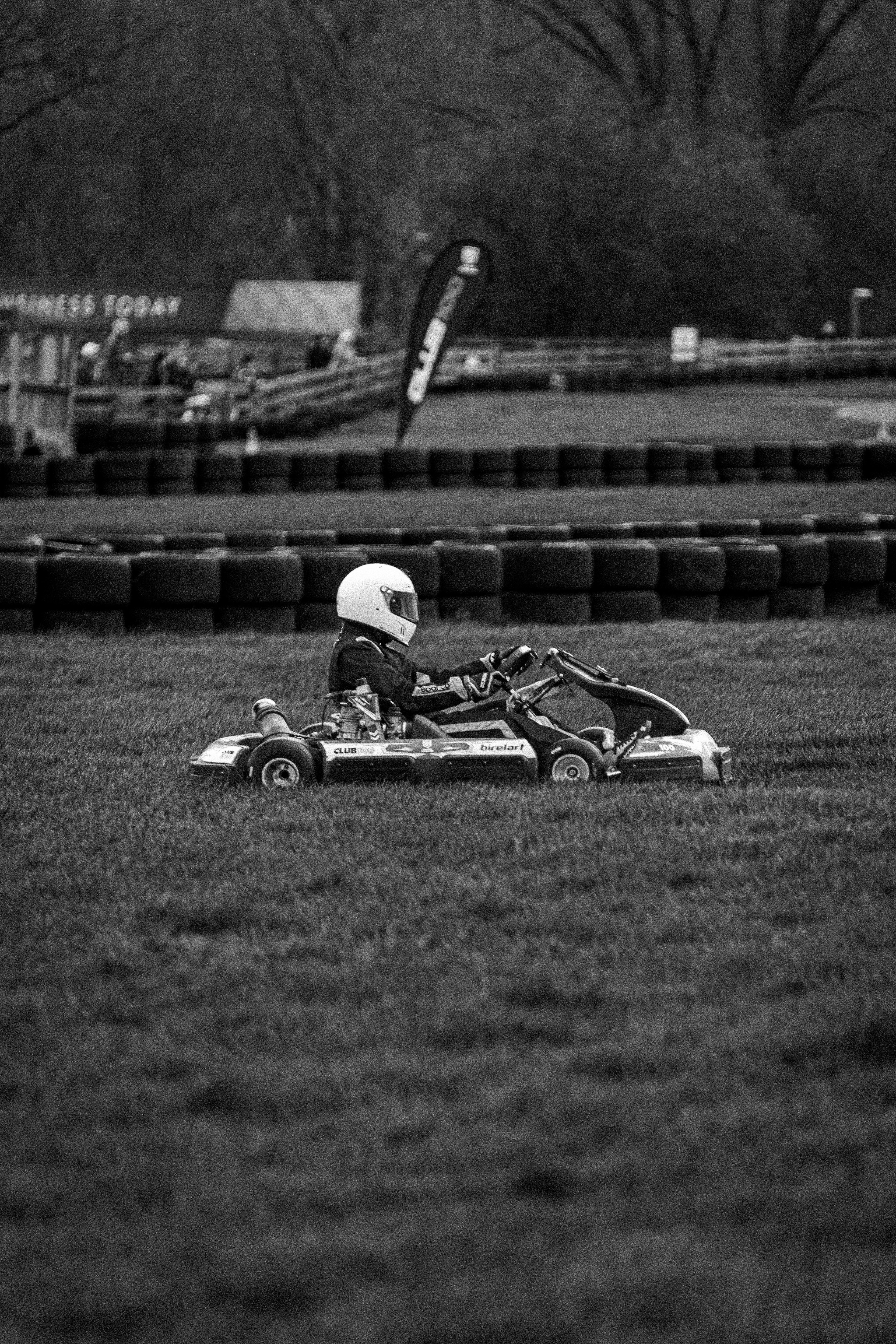 Go-kart dengan pengemudi di rumput di samping trek balap.