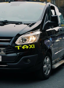 A black taxi cab with its headlight on