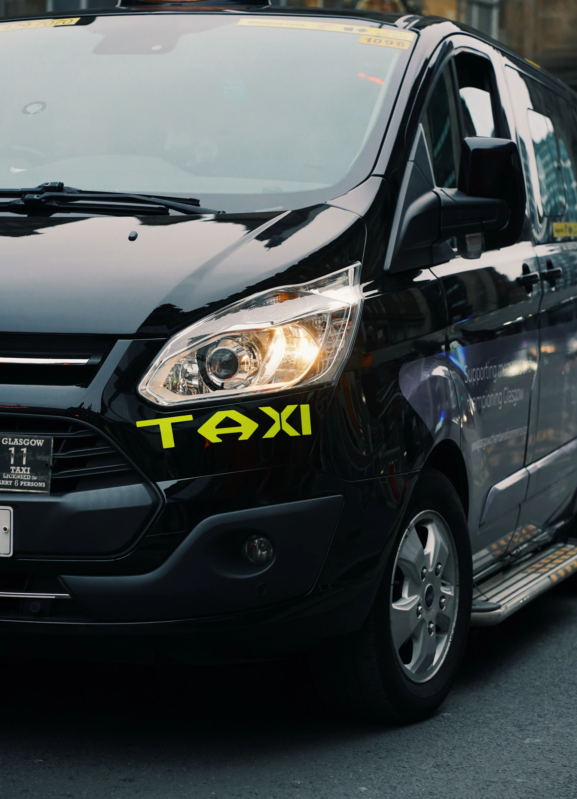 A black taxi cab with its headlight on.