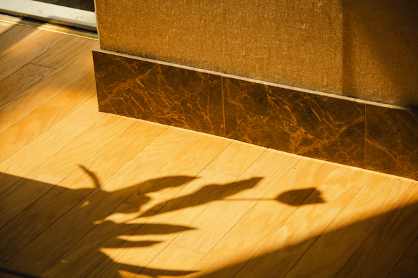 Tulip and leaf shadows on a sunlit wooden floor.
