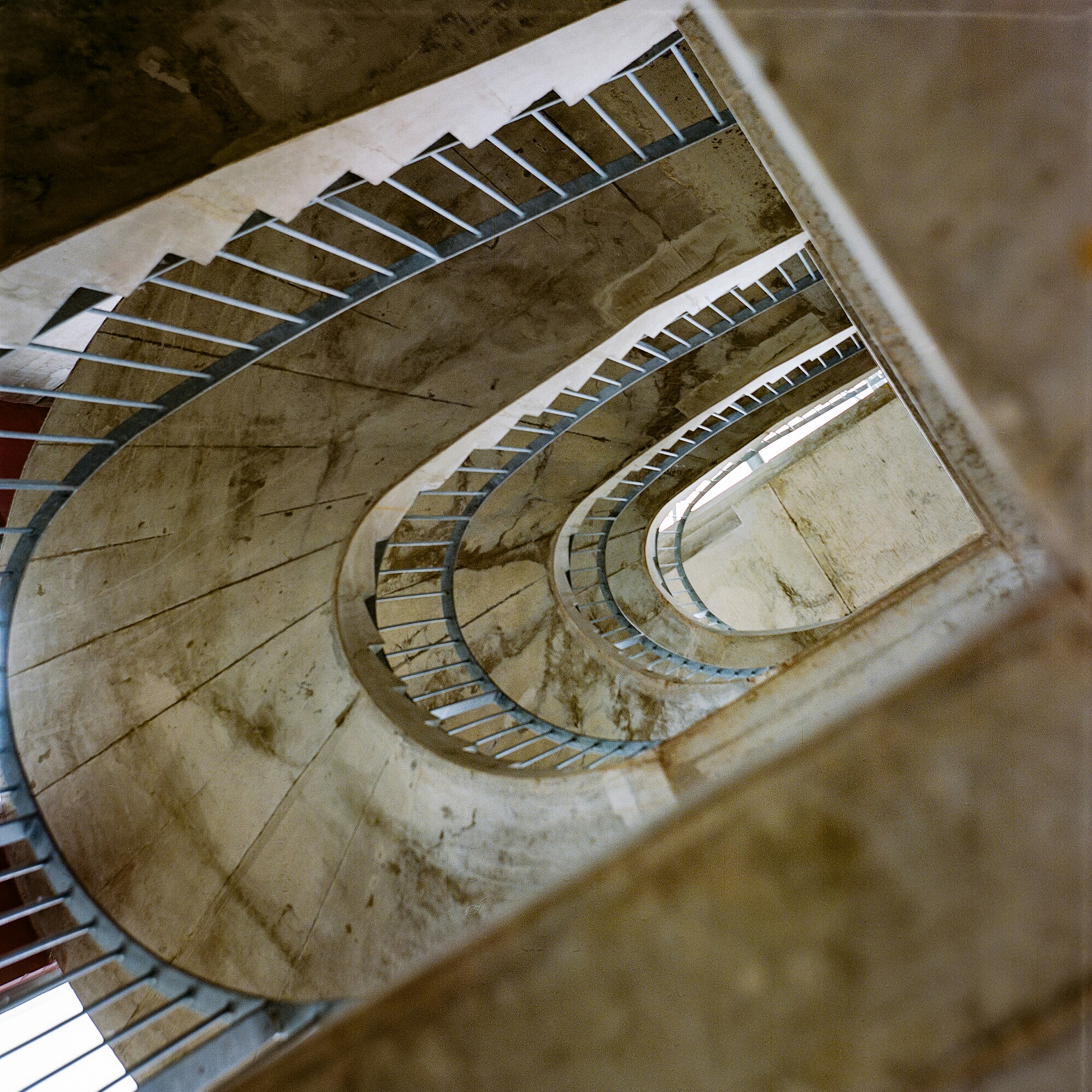 A concrete spiral staircase with metal railings viewed from above
