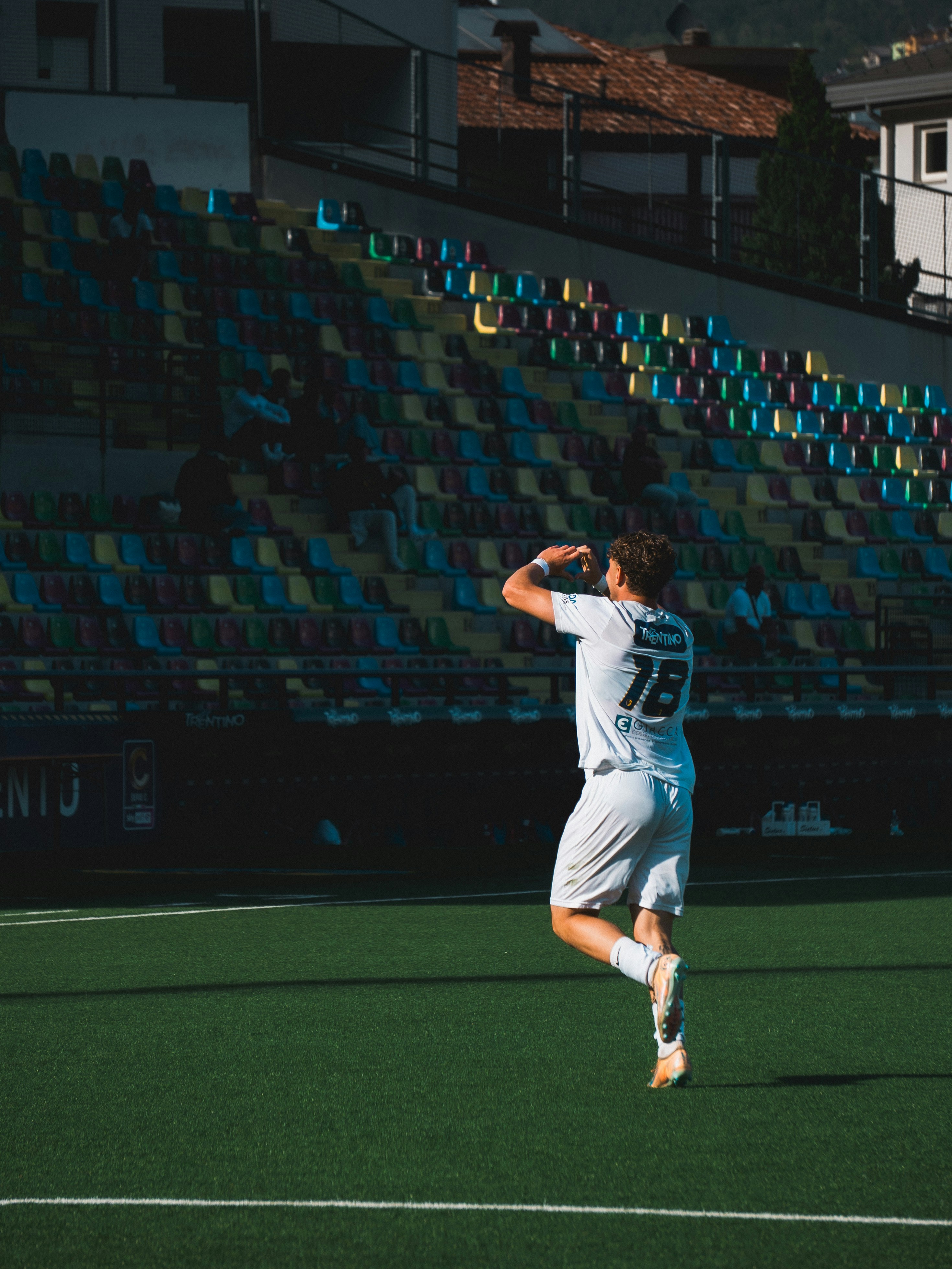 Pemain sepak bola berseragam putih merayakan di lapangan hijau.