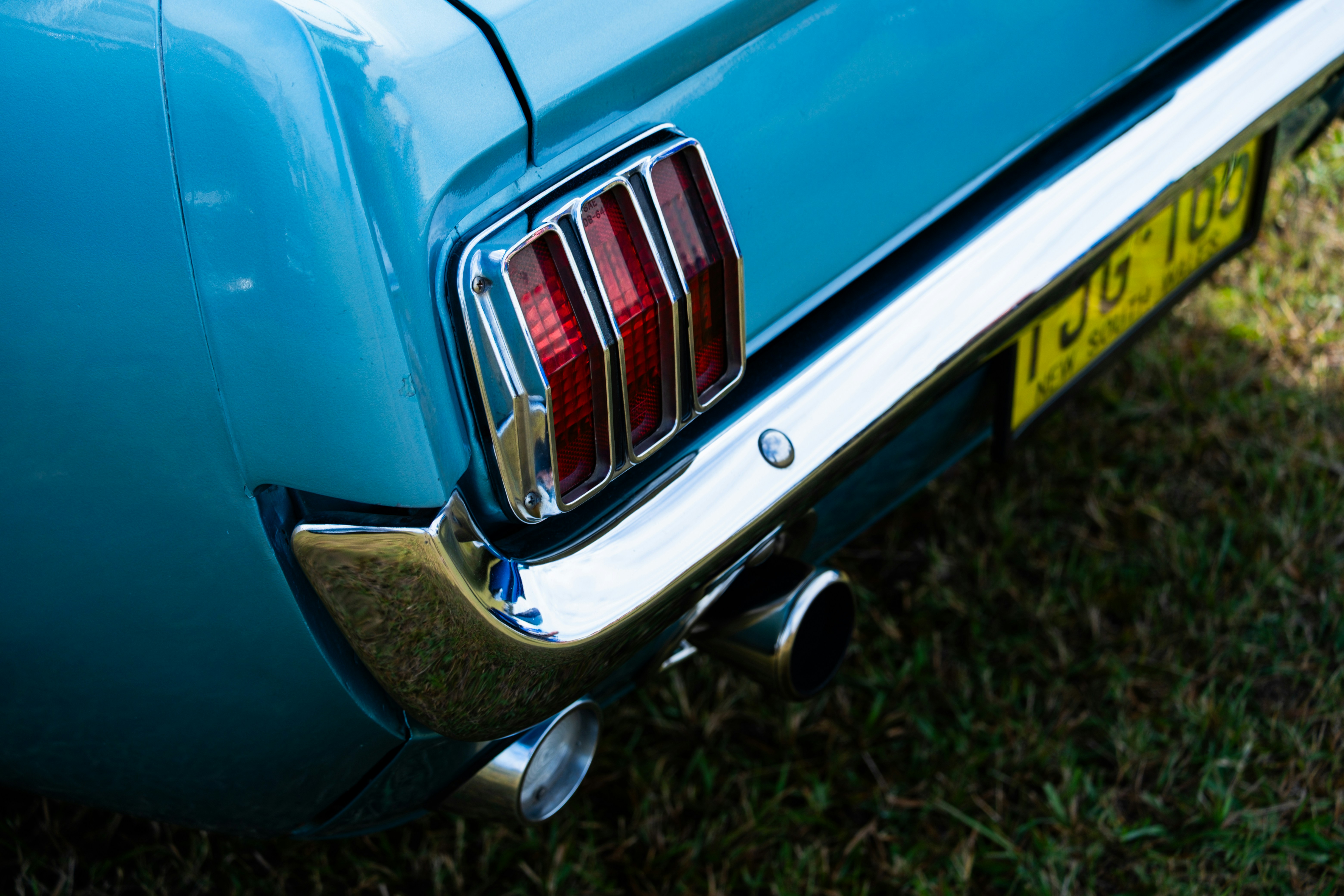 Close da lanterna traseira e escapamento de um carro azul vintage.