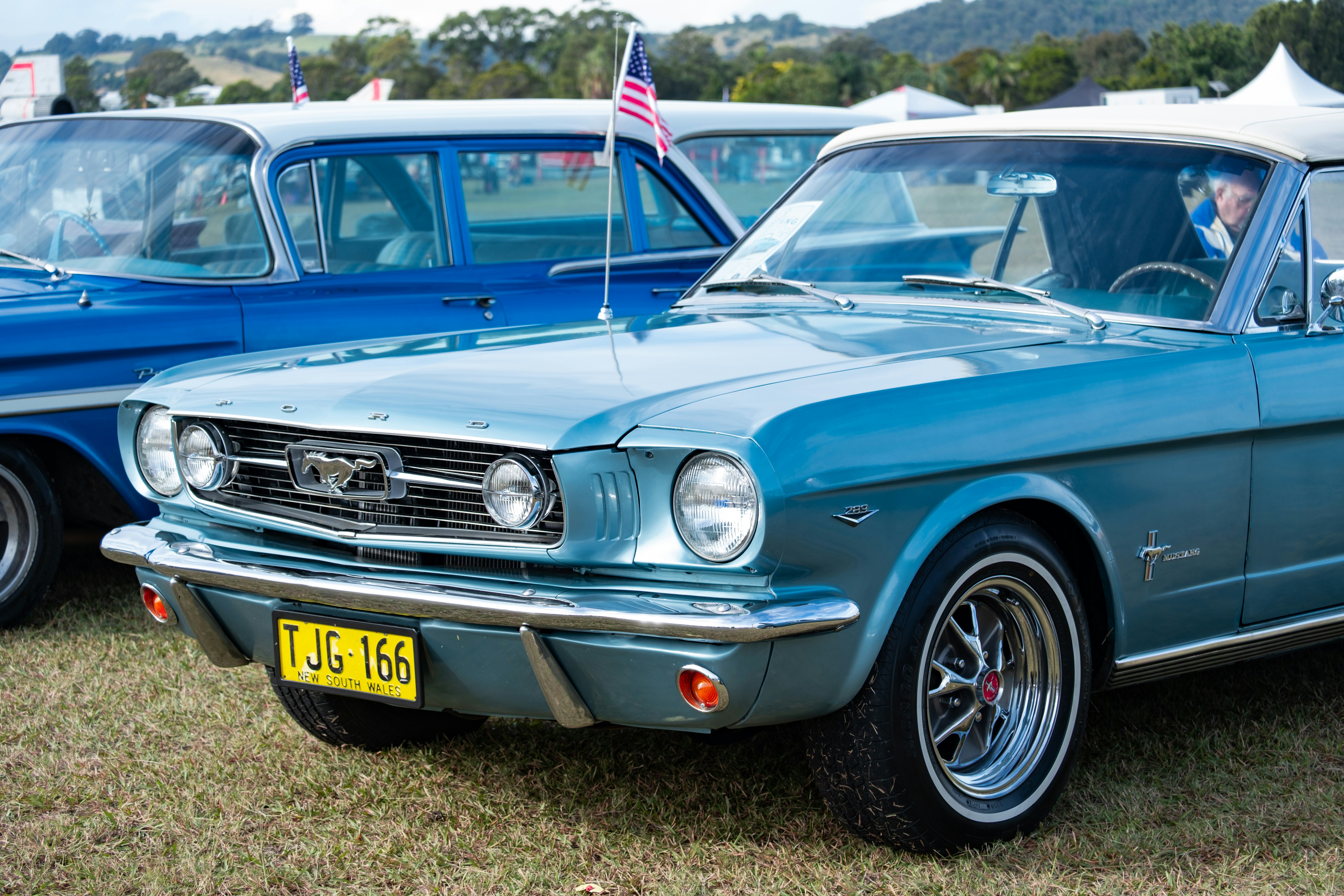 Um carro clássico azul claro com uma bandeira americana.