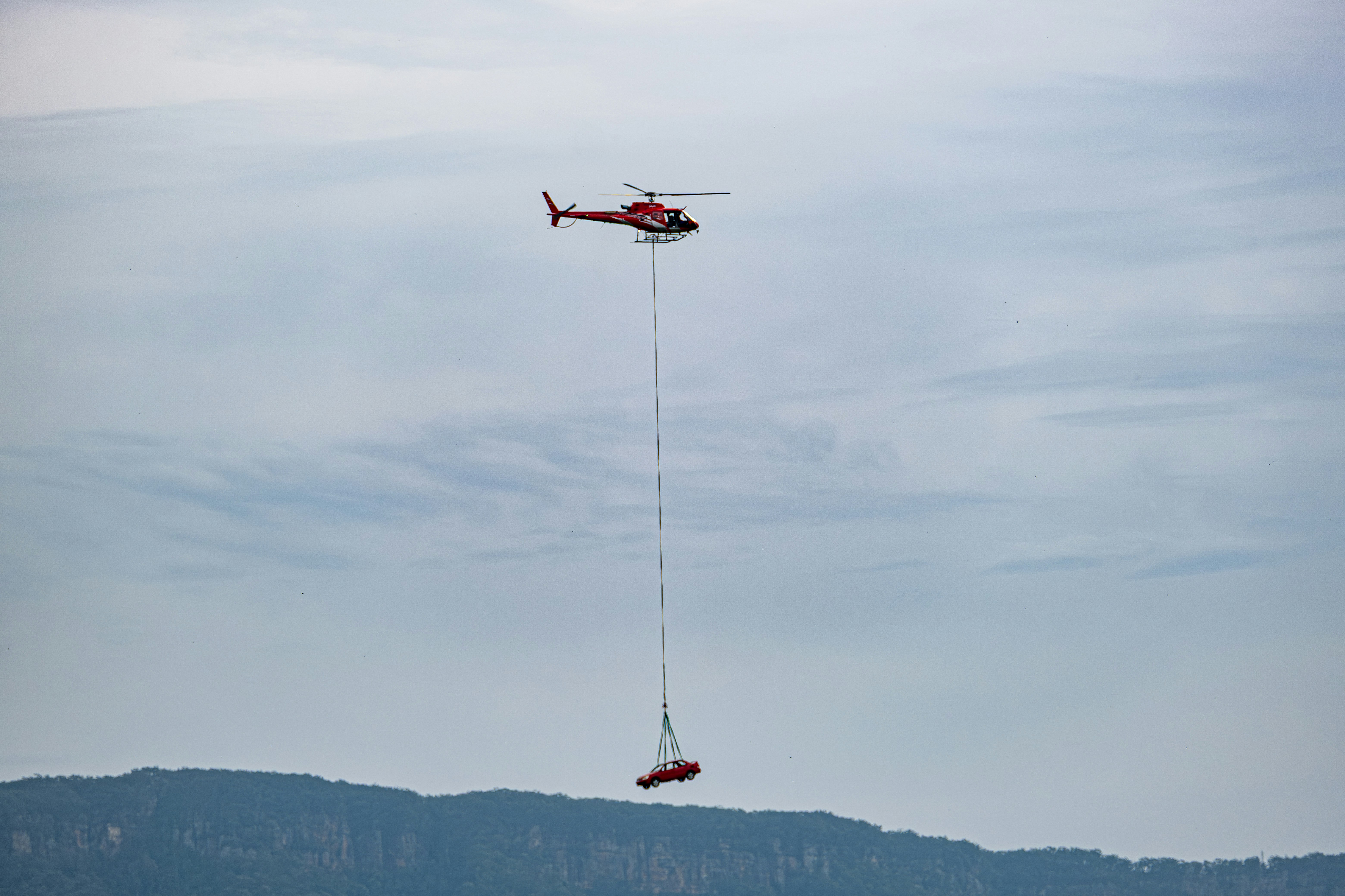 Helicopter carrying a load suspended by a cable.