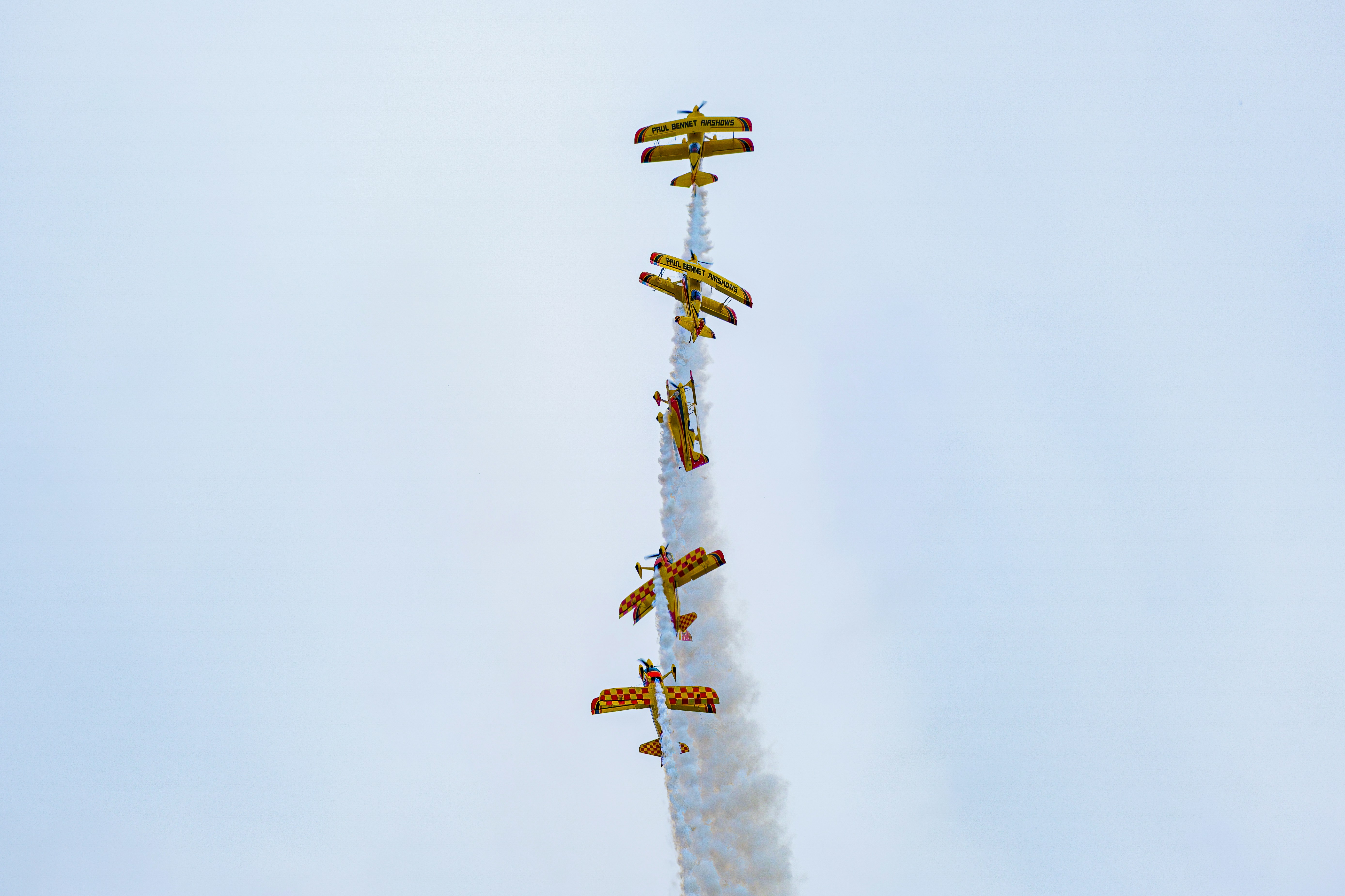 Biplanos amarelos realizam manobras acrobáticas no céu