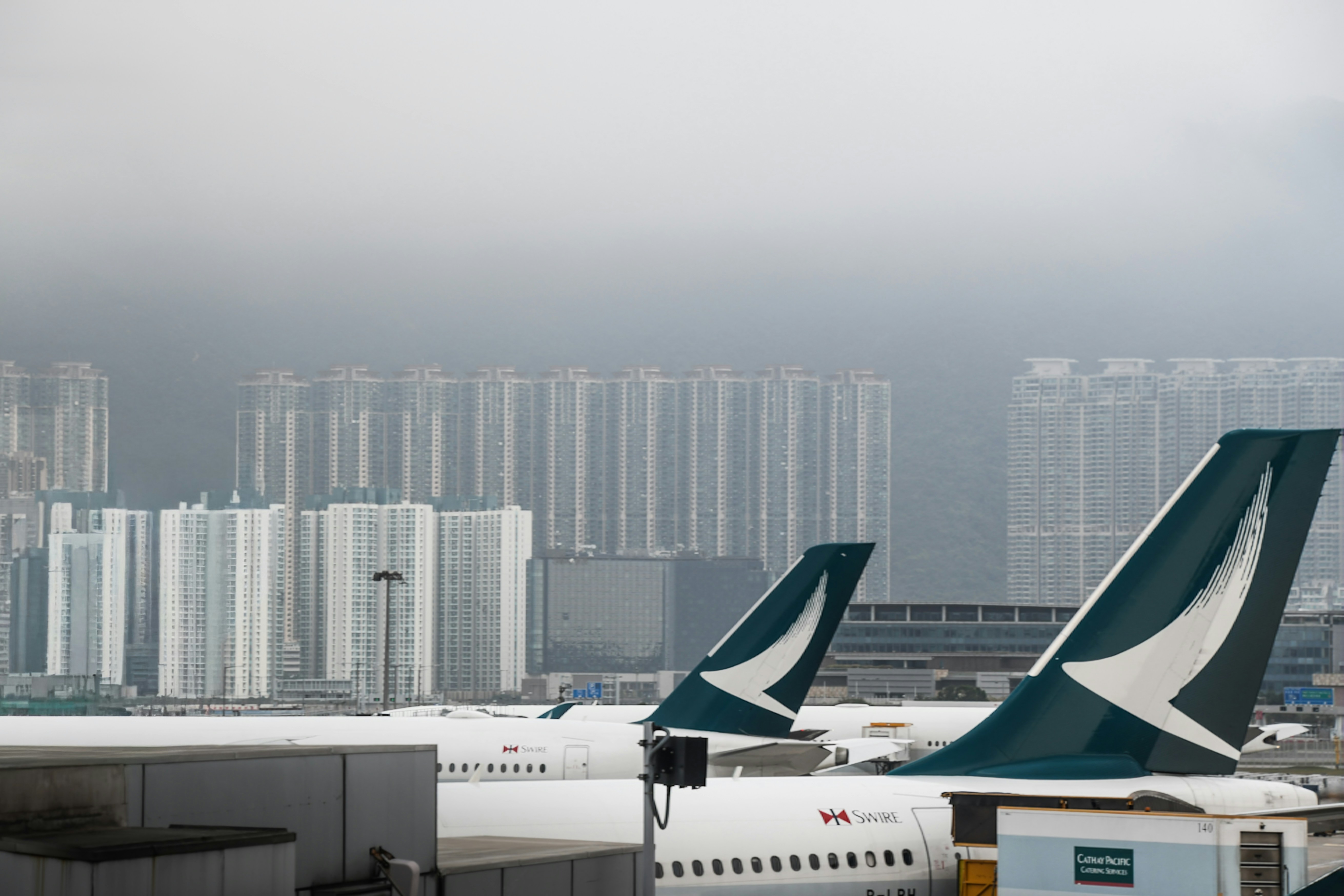 Two airplanes with green tails parked at airport.