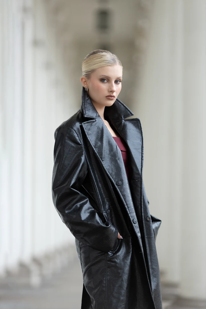 Editorial photograph of a long black trench-style coat worn outdoors