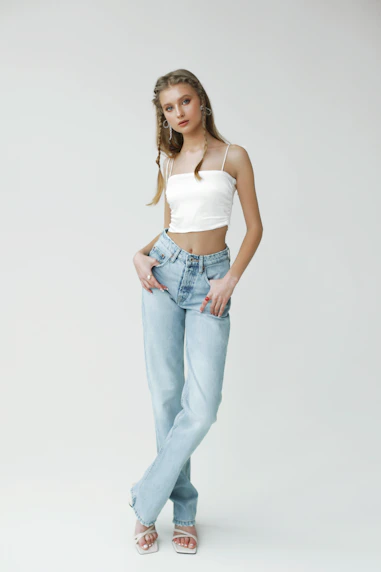 A young woman in a white crop top and jeans