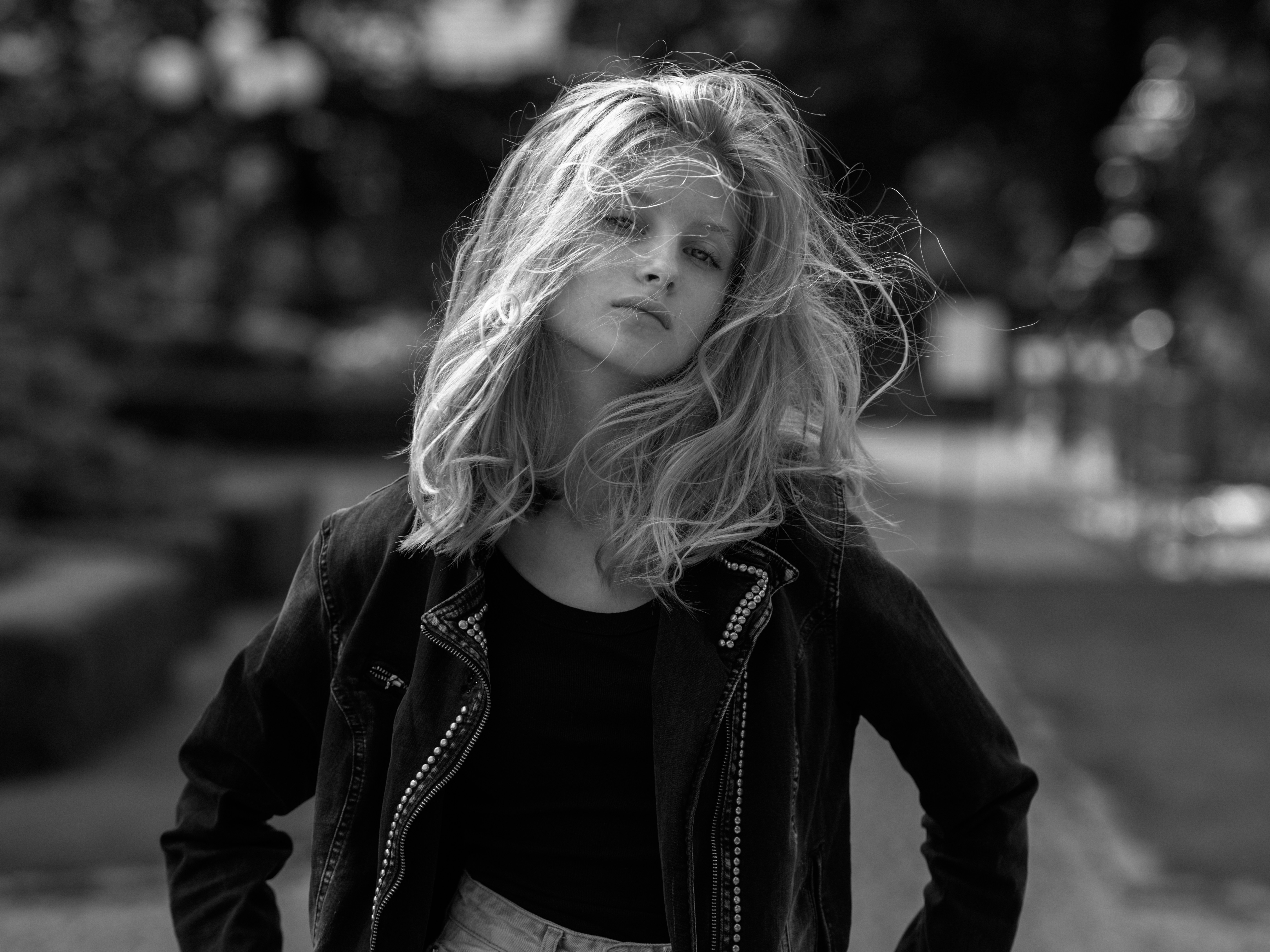 A young woman with wind-blown blonde hair and leather jacket.