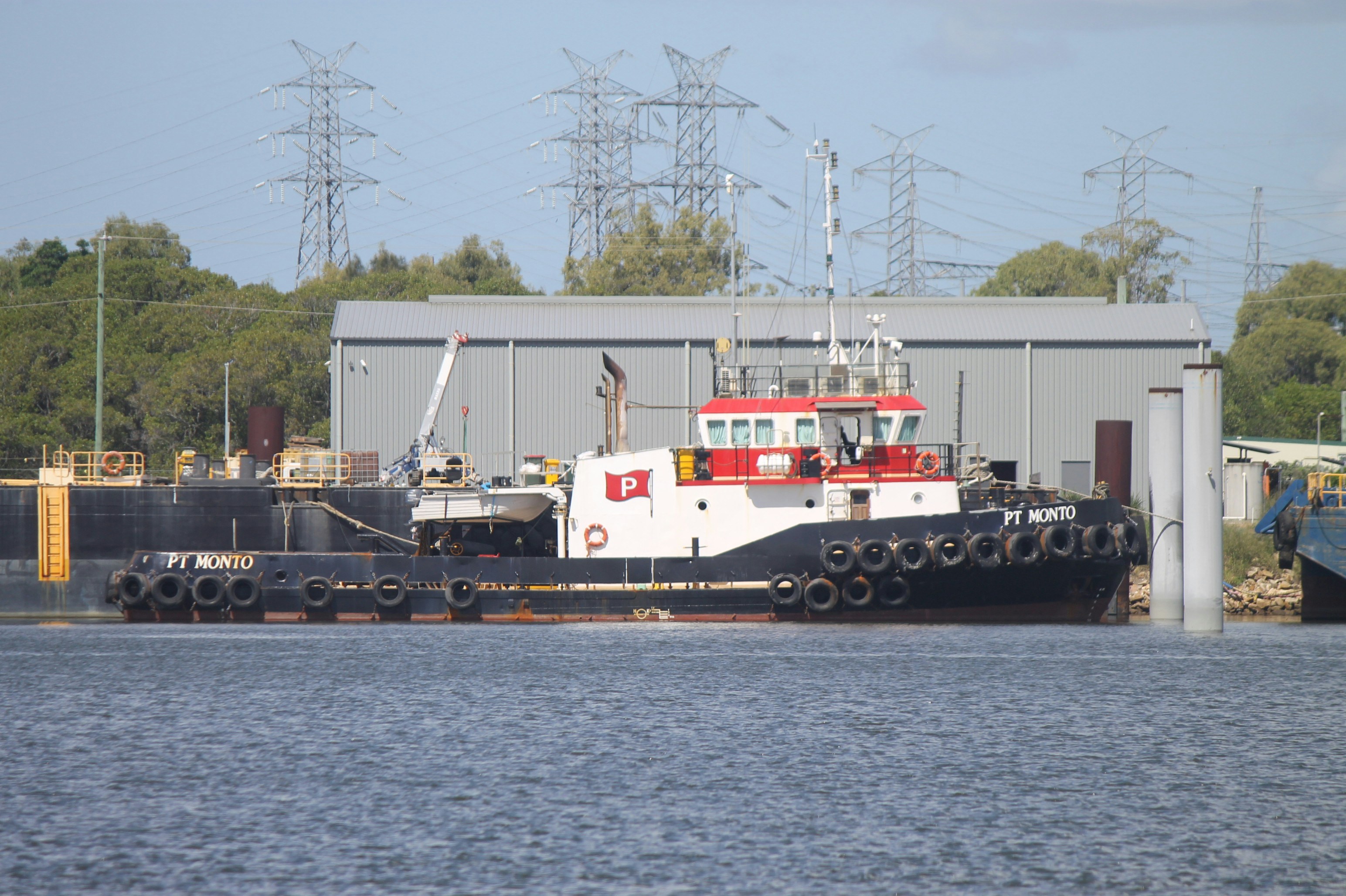A red and white tugboat docked near a building.