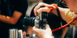 Person holding a camera with a red strap