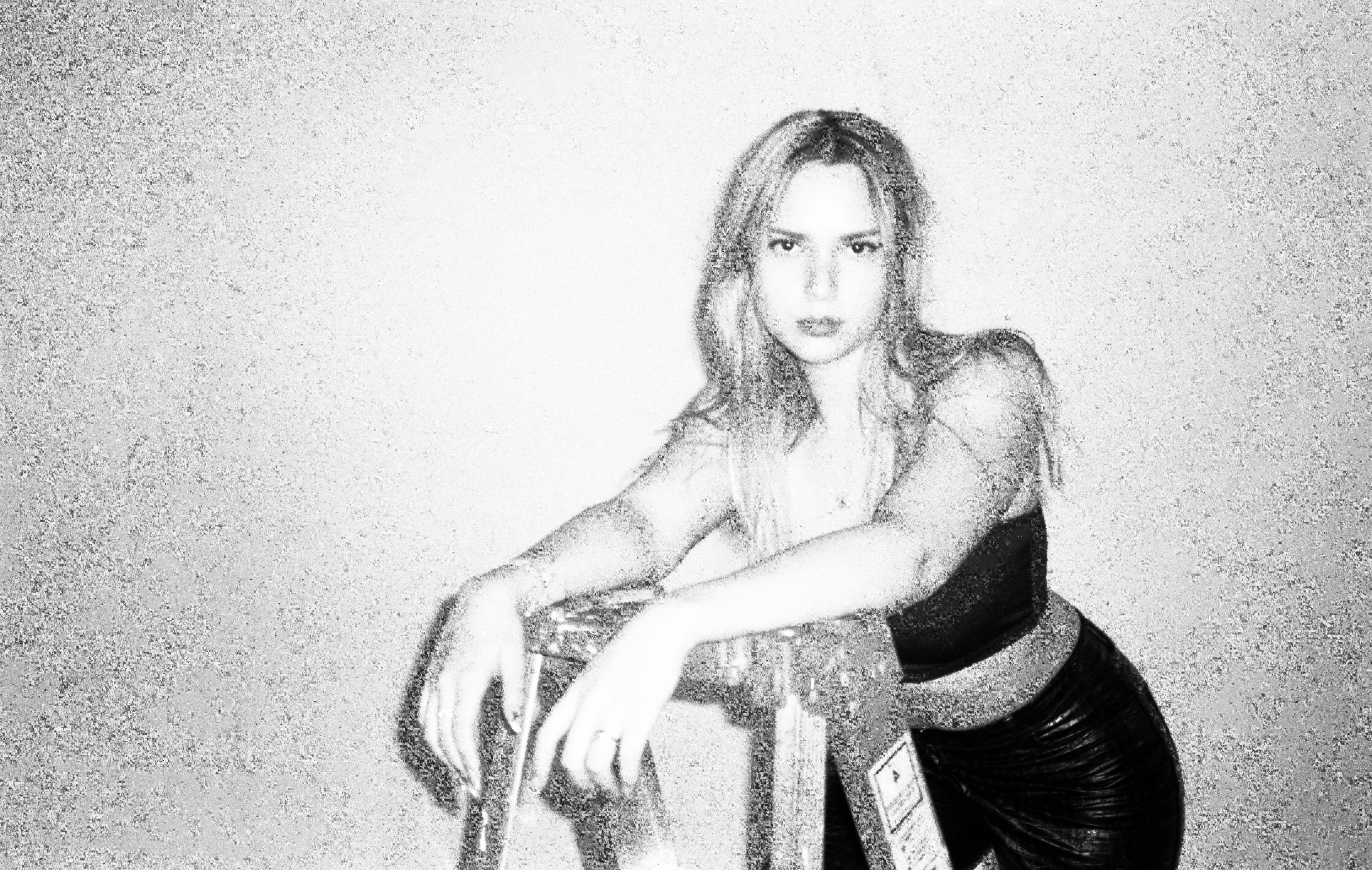 A blonde woman leans on a ladder