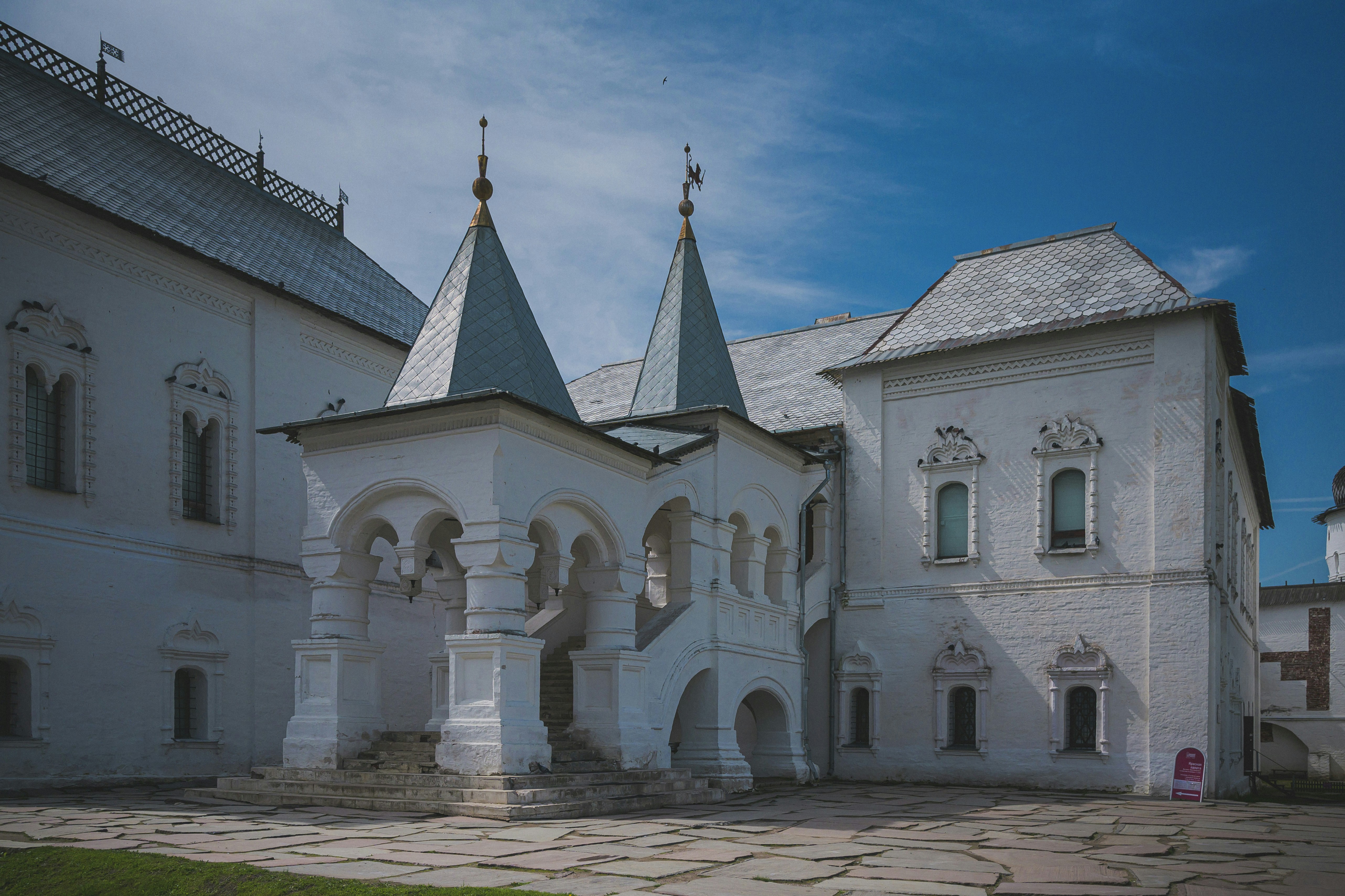White historic building with pointed roofs and arched windows.