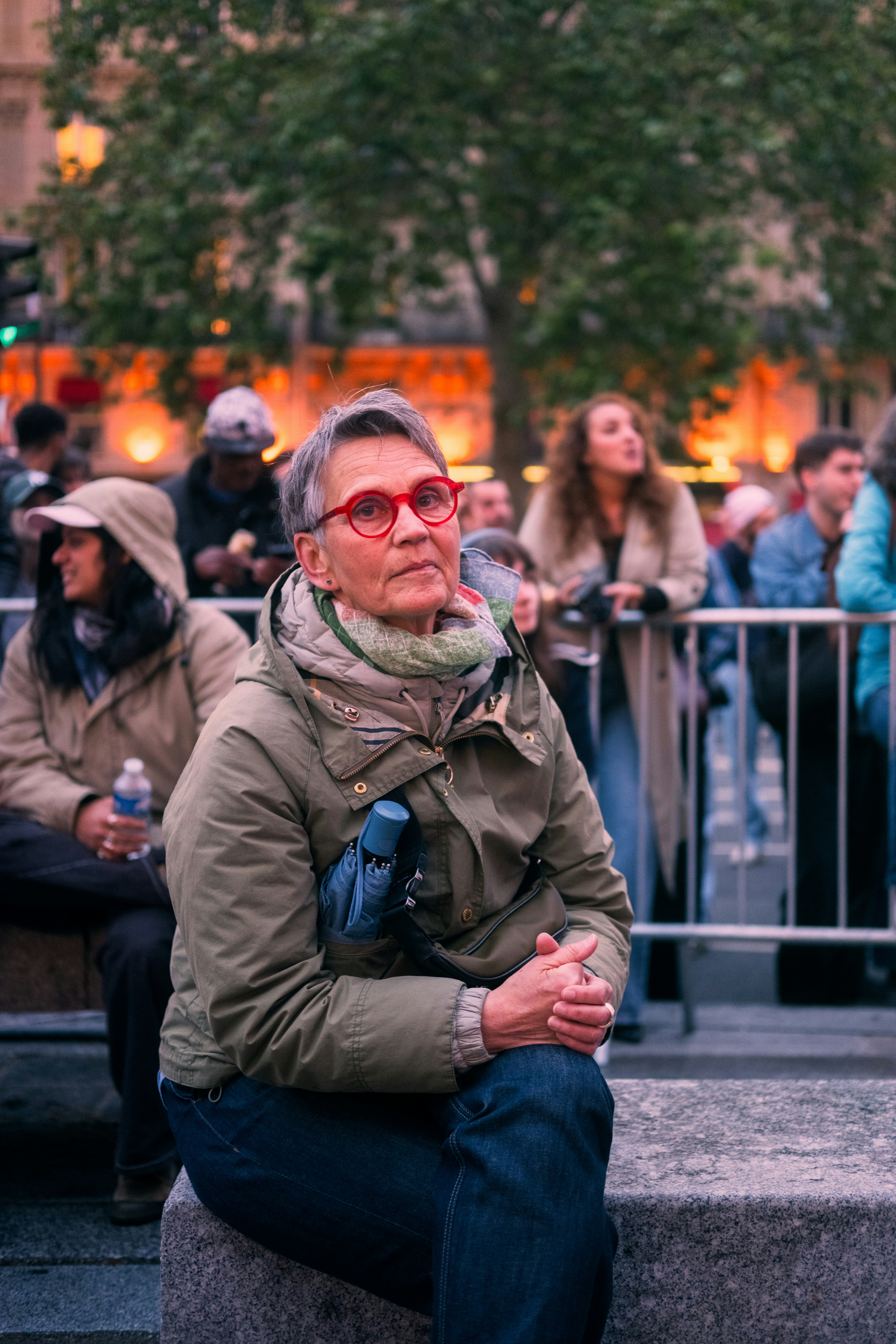 Frau mit Brille beobachtet eine Veranstaltung draußen