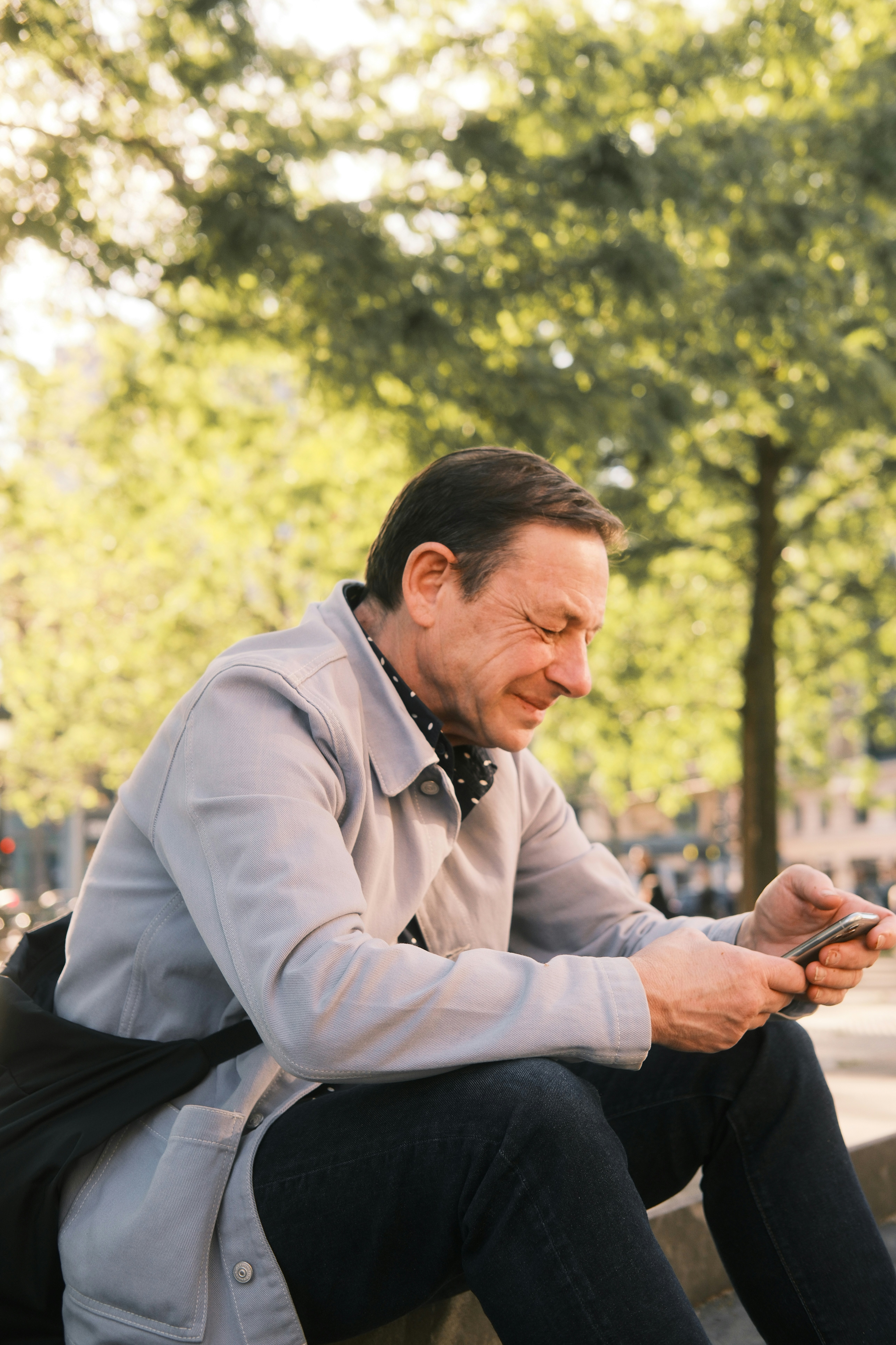 Mann sitzt draußen und schaut auf sein Handy