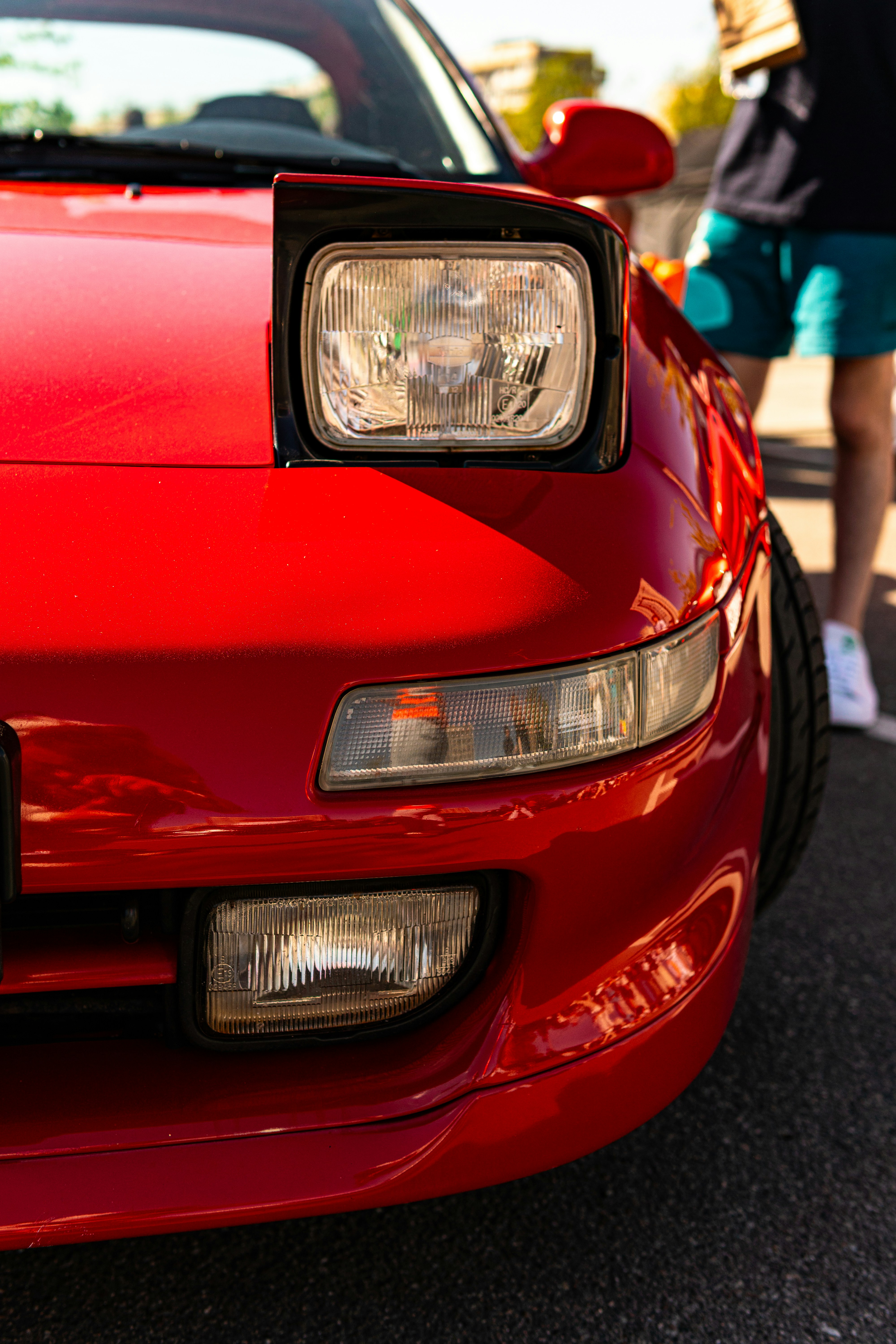 Mobil sport merah dengan lampu depan pop-up terbuka.
