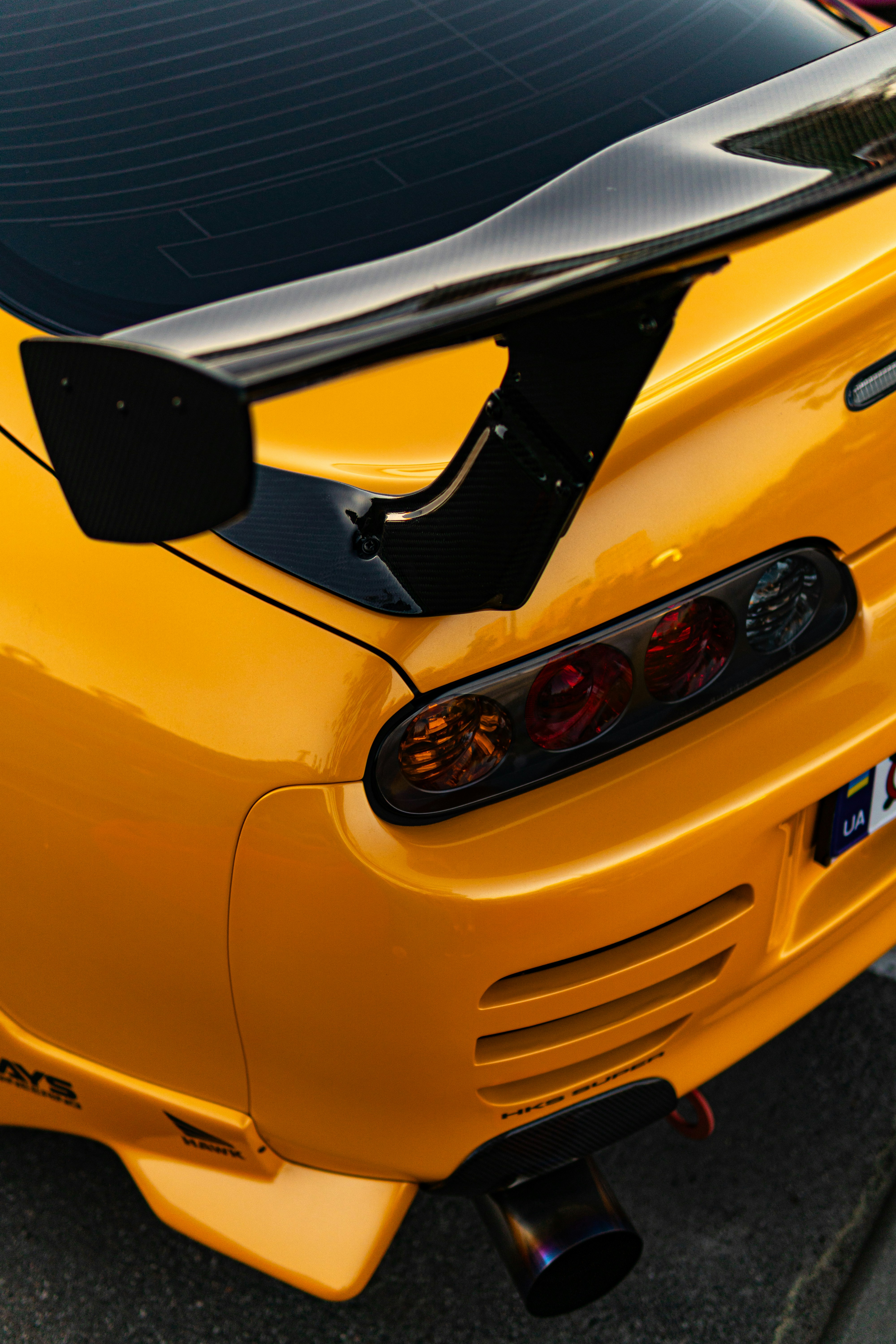 Yellow sports car's rear with spoiler, taillights, and exhaust. photo ...