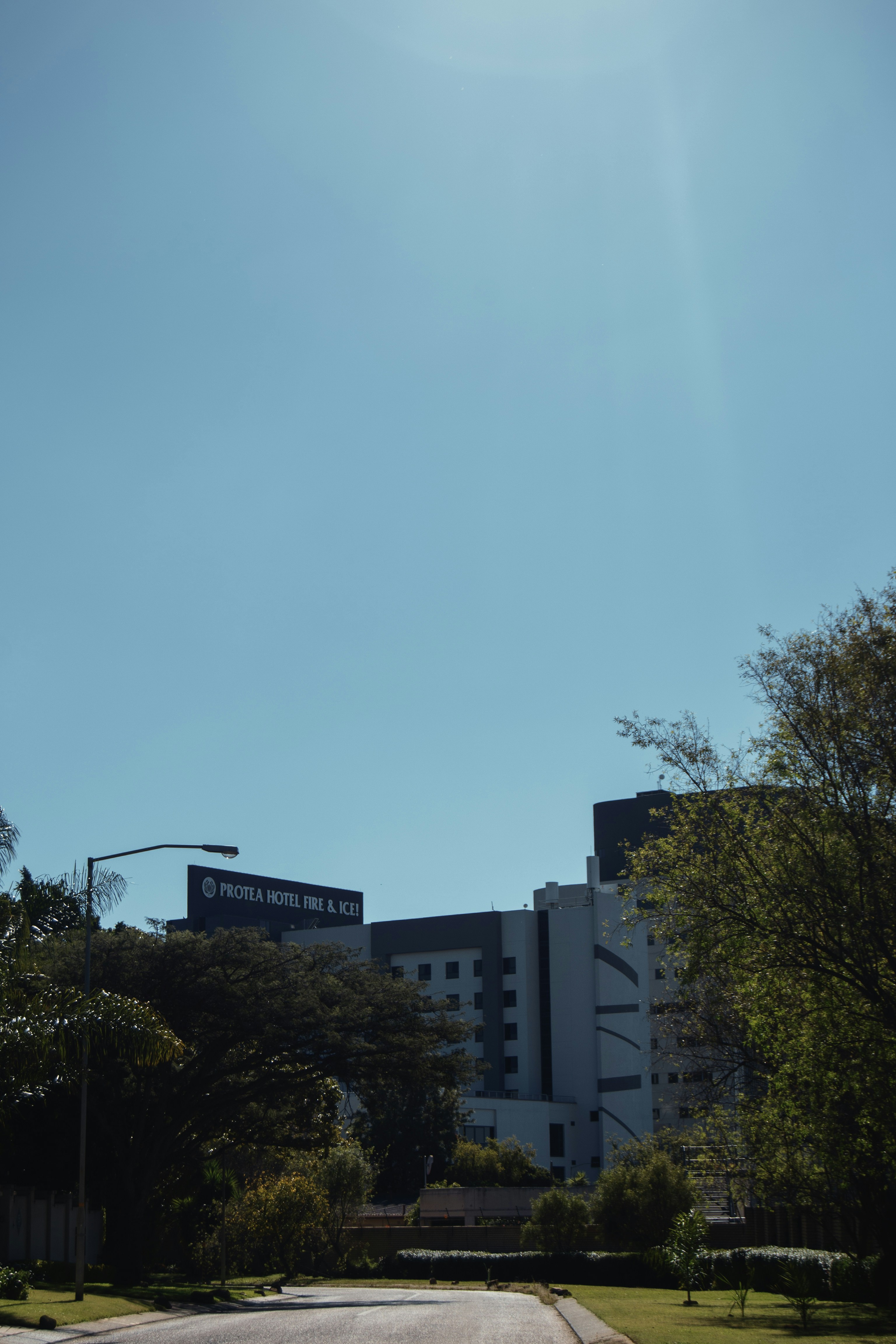 Modern hotel building surrounded by green trees under clear sky