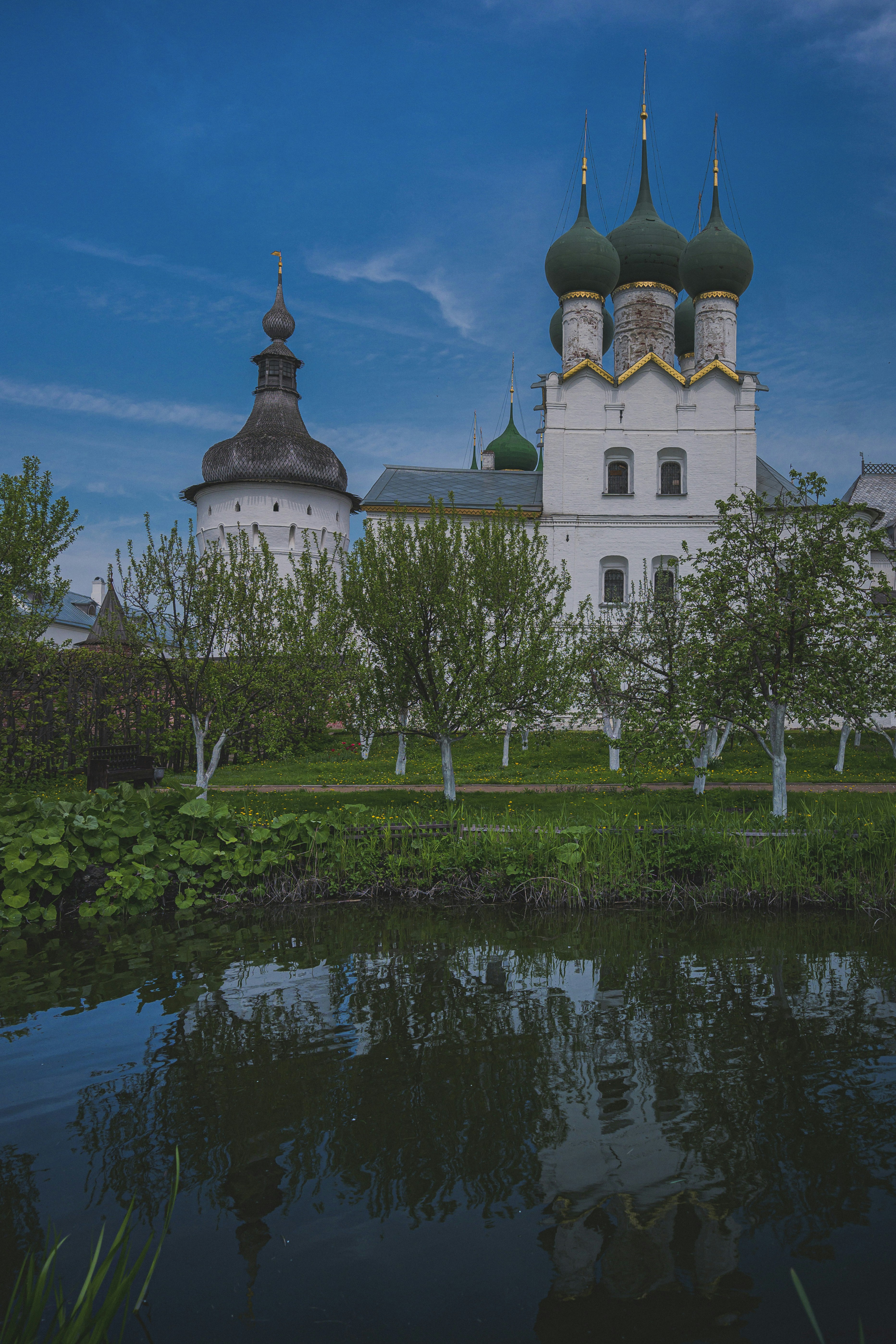 Ancient russian monastery with green domes reflected in still water.