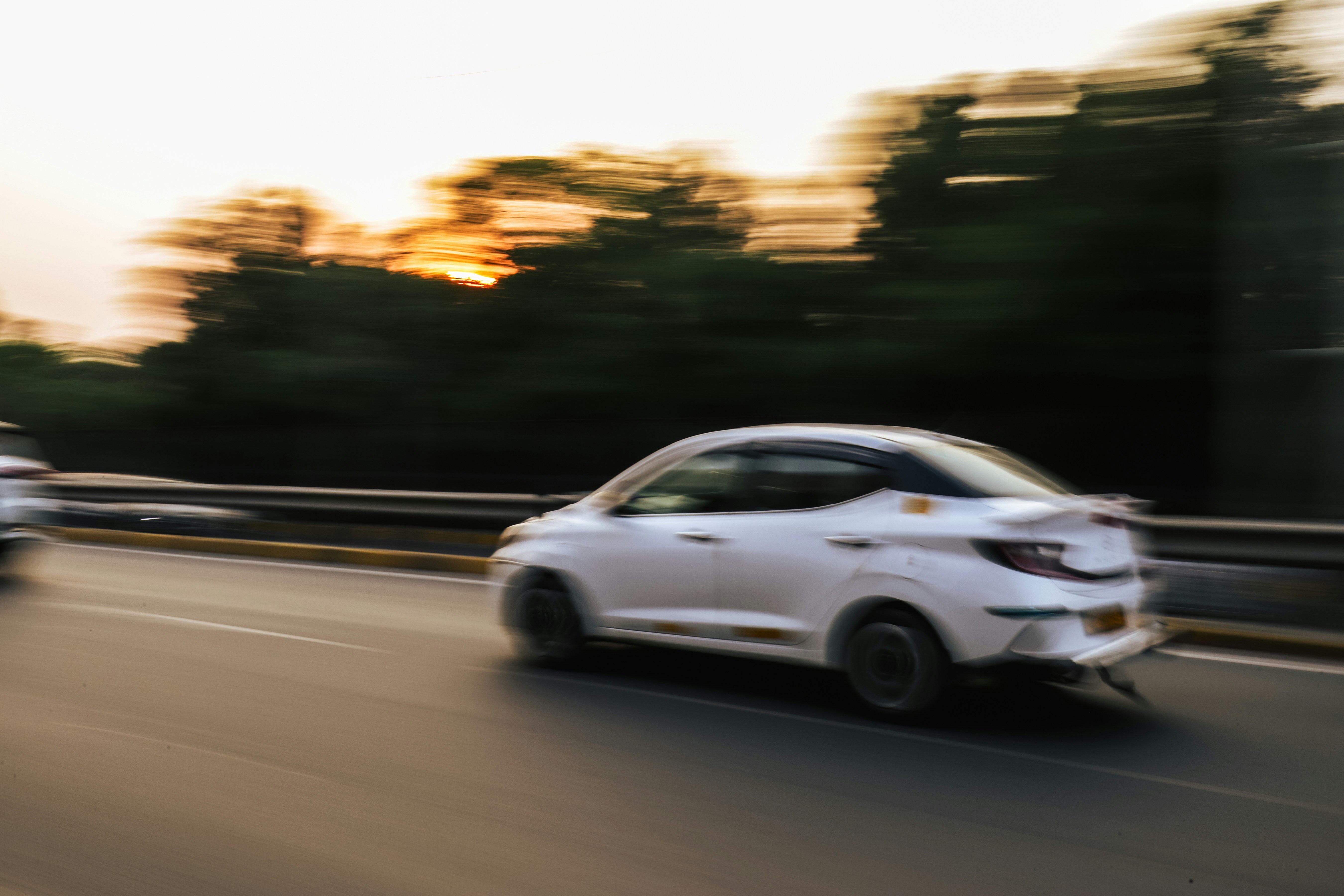 White car in motion blur on a road during sunset.