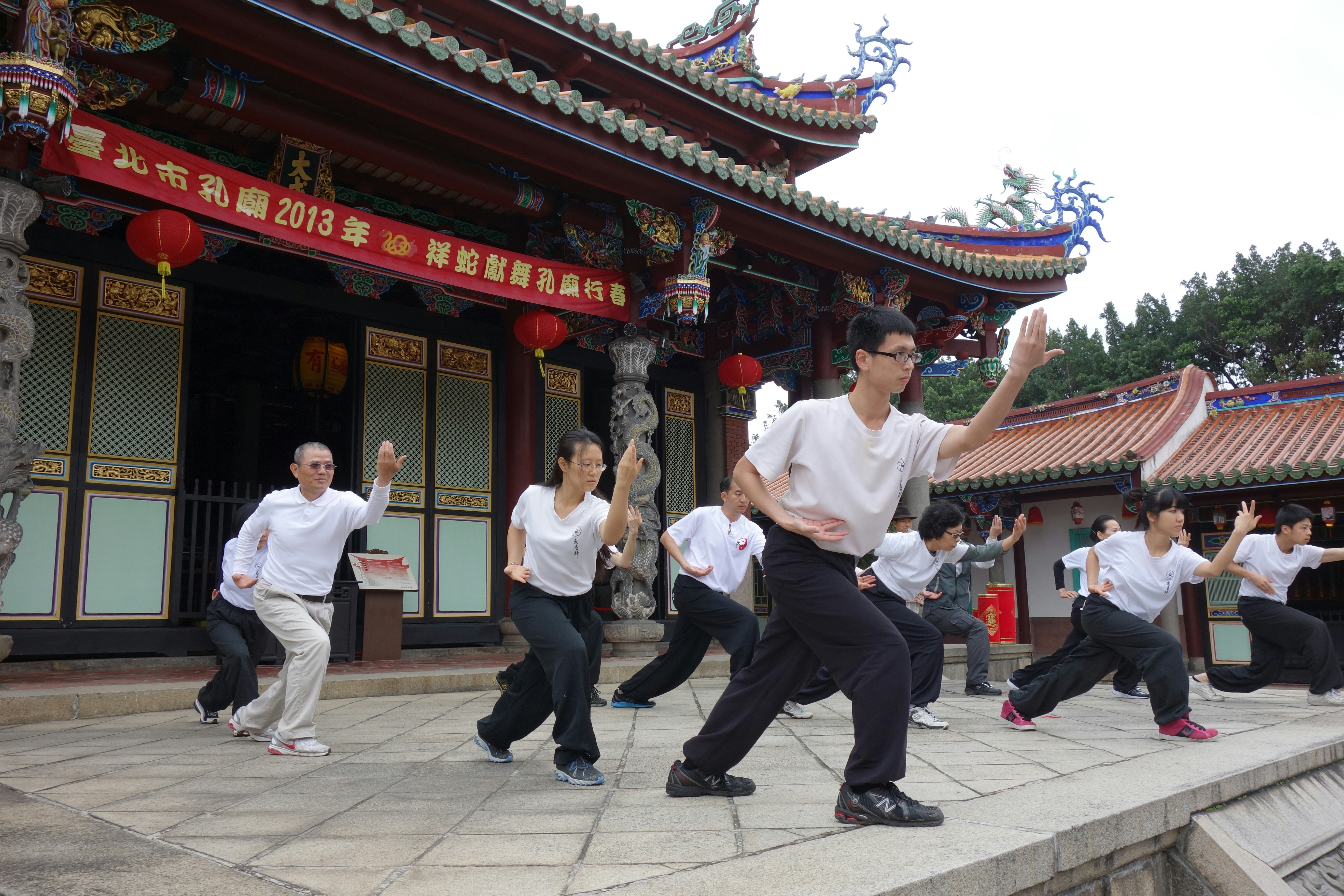 People practicing martial arts in front of a traditional temple.