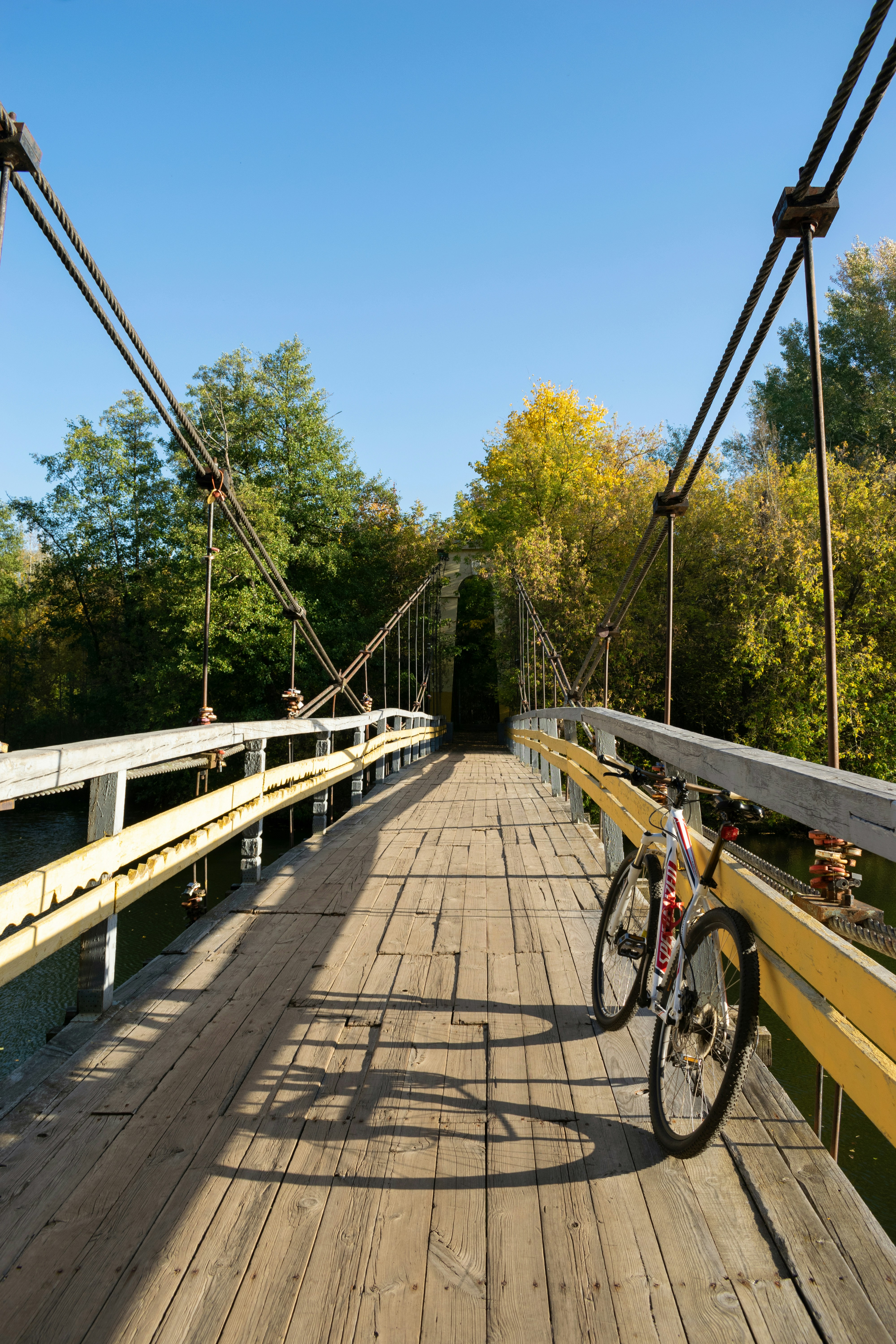 Bicycle on a wooden suspension bridge under a clear sky.