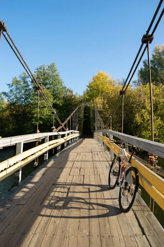 Bicycle on a wooden suspension bridge under a clear sky.