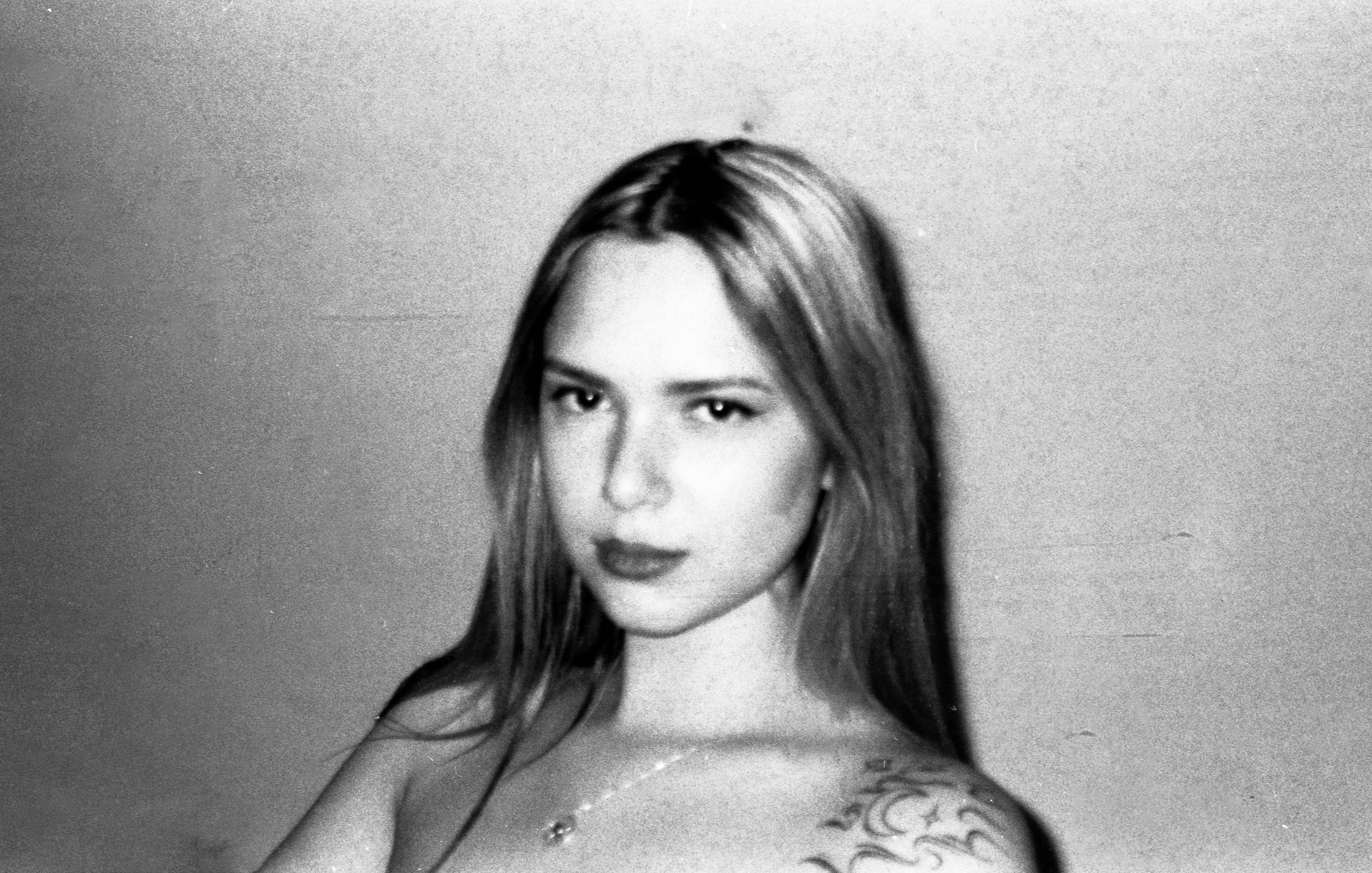 Serious young woman with long hair and shoulder tattoo.