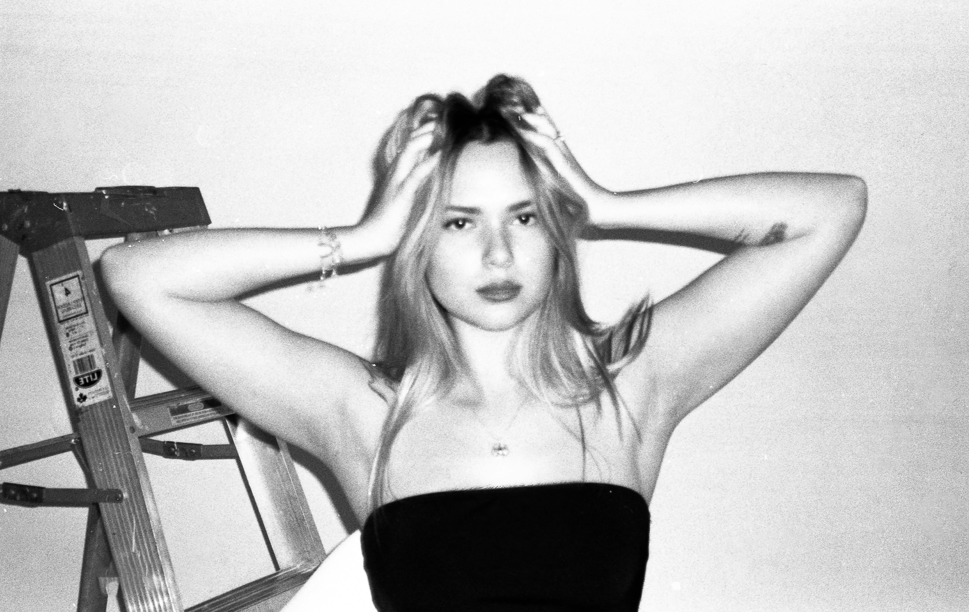 A young woman posing with hands in her hair.
