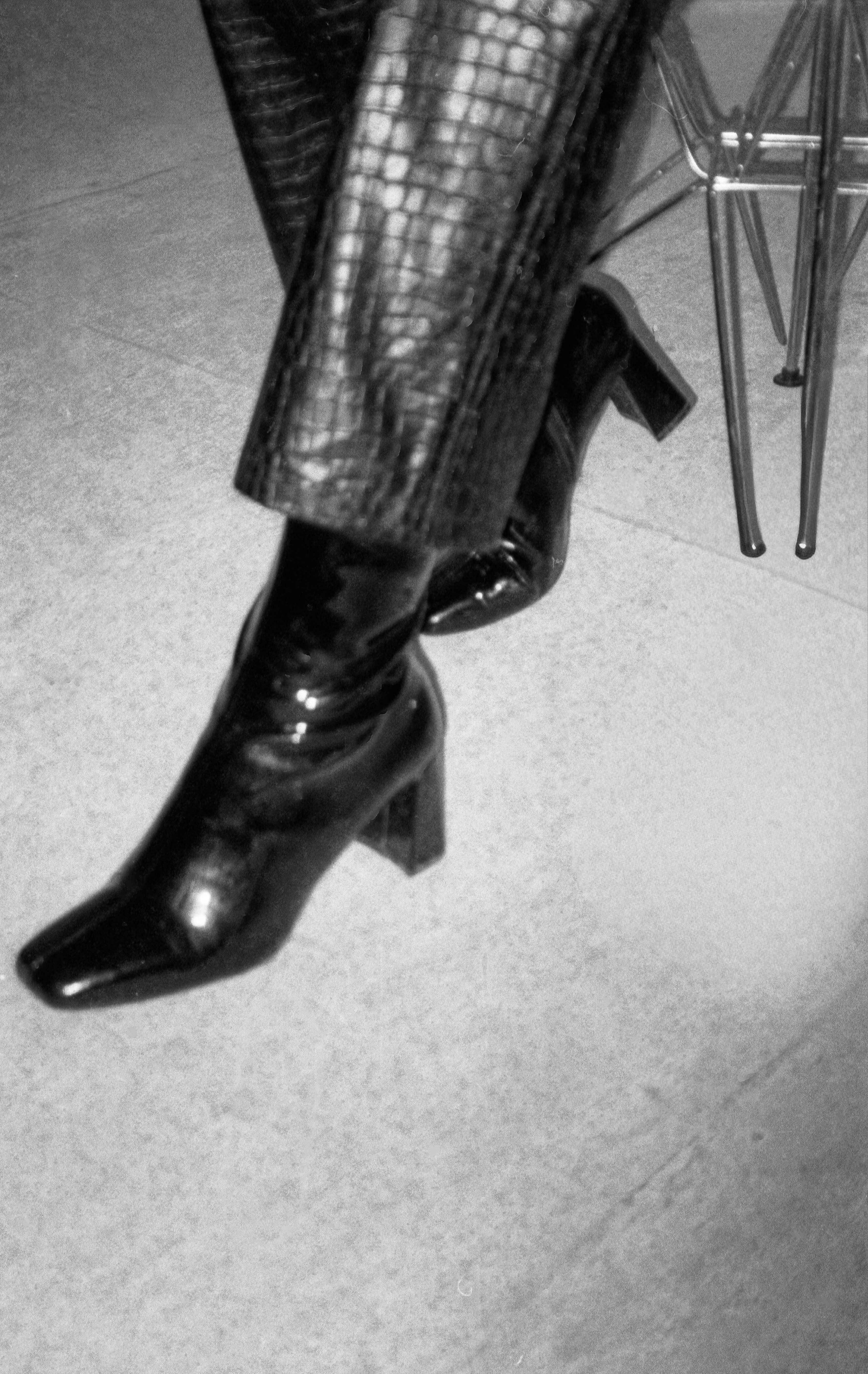Crossed legs in textured pants and shiny heeled boots.