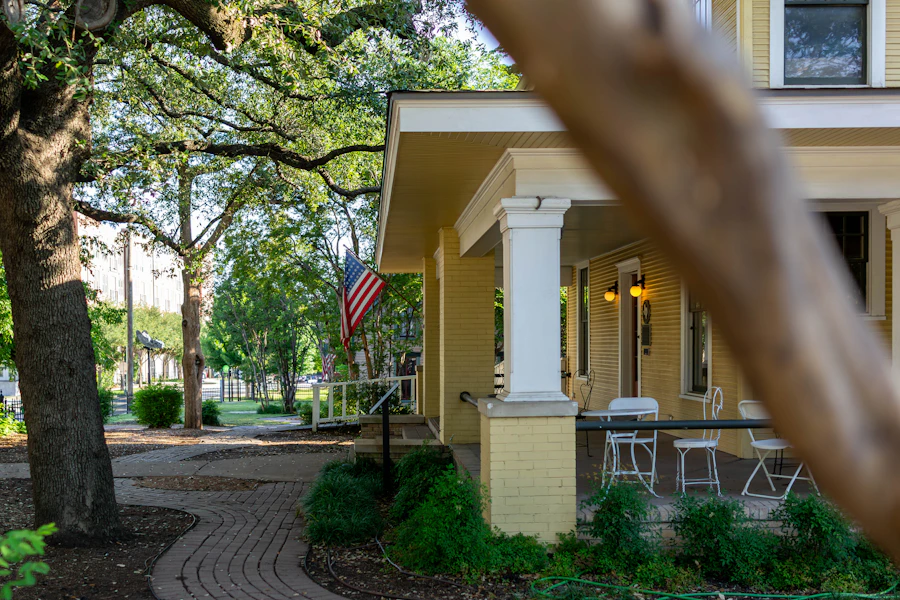 A yellow porch with columns and a brick walk