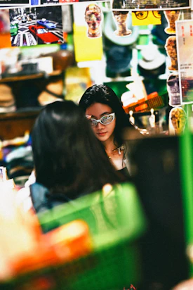 Stylish woman wearing silver glasses in a busy, decorated space.