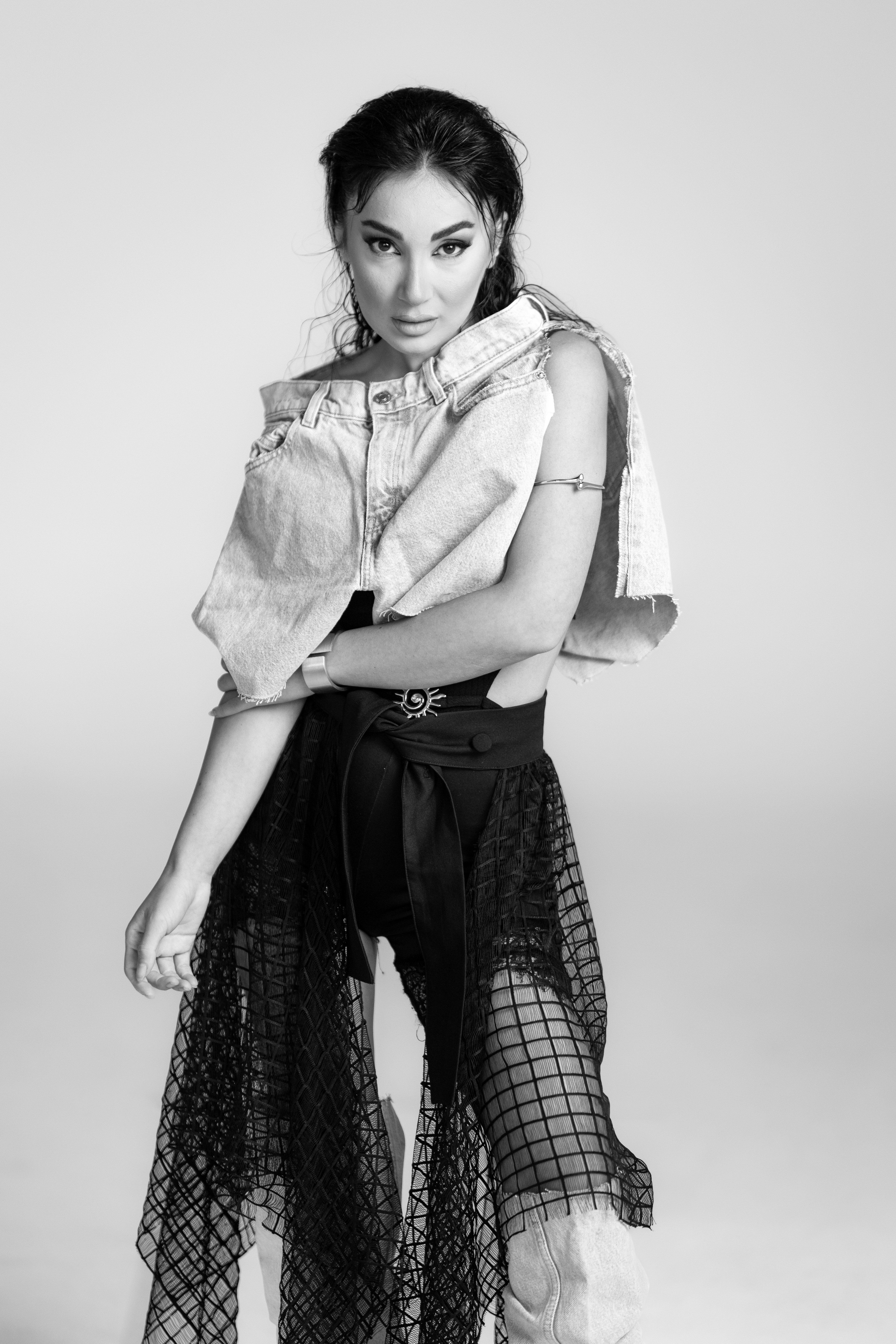 Stylish woman in denim and sheer skirt poses.