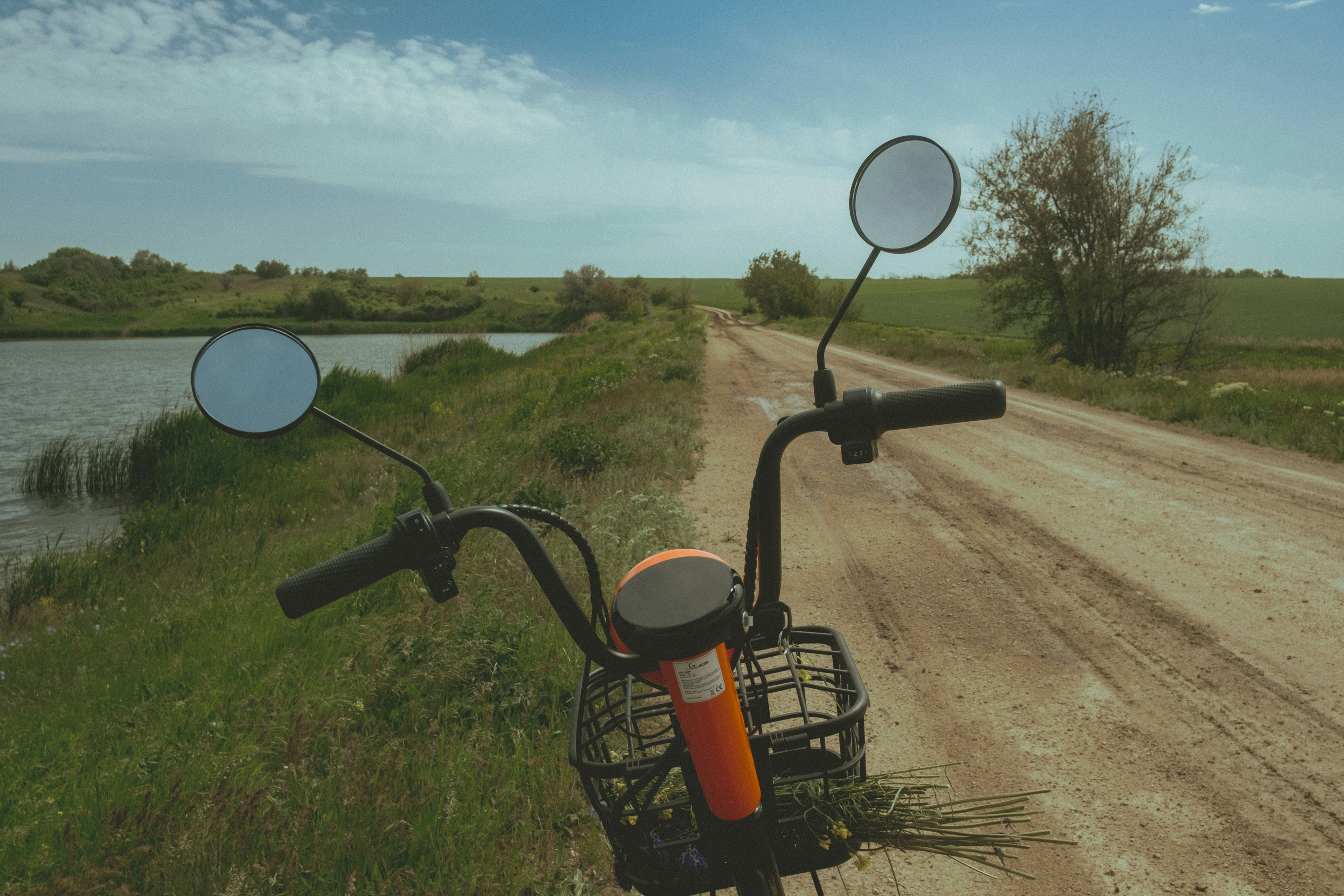 Scooter handlebars on a rural dirt road beside water. photo – Free ...