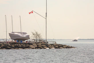 A sailboat on a rocky pier with a canadian flag.