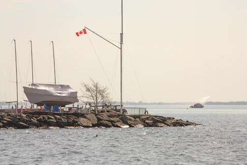A sailboat on a rocky pier with a canadian flag.