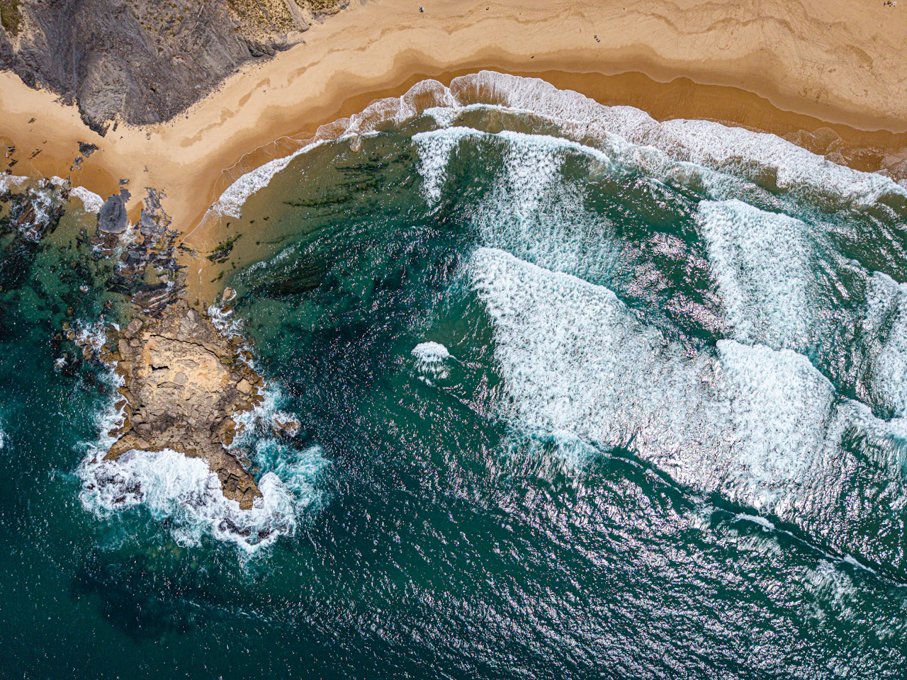 Ocean waves crashing on a sandy beach and rocky coastline