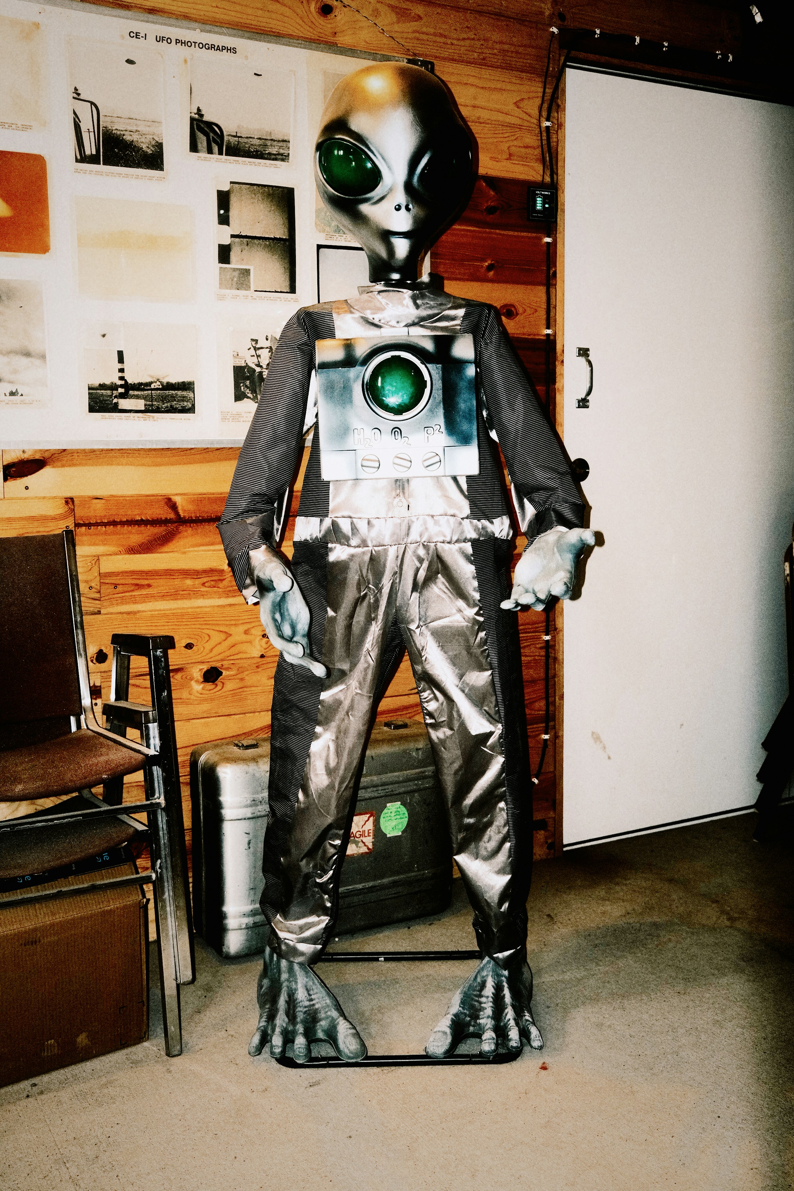 A grey alien mannequin with a camera on its chest.