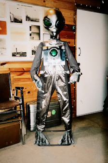 A grey alien mannequin with a camera on its chest.