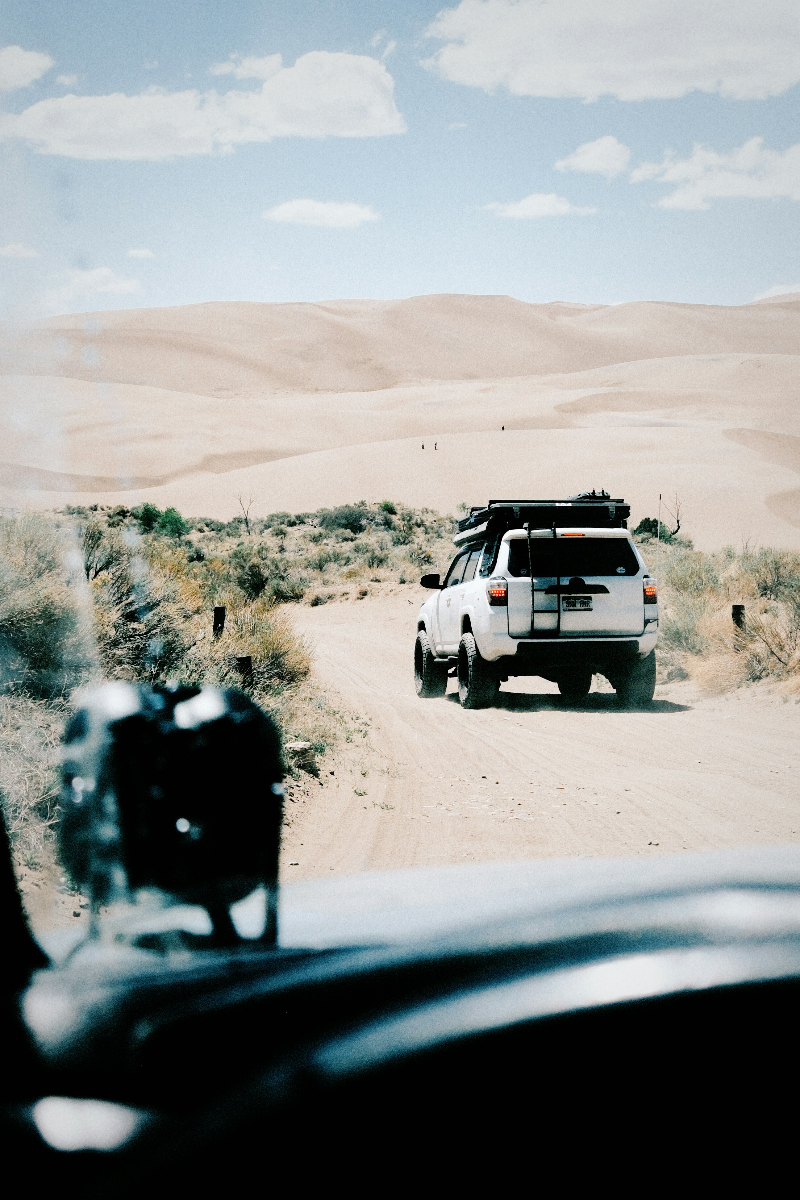 Dirigindo em SUV por uma estrada de terra em direção a grandes dunas do deserto.