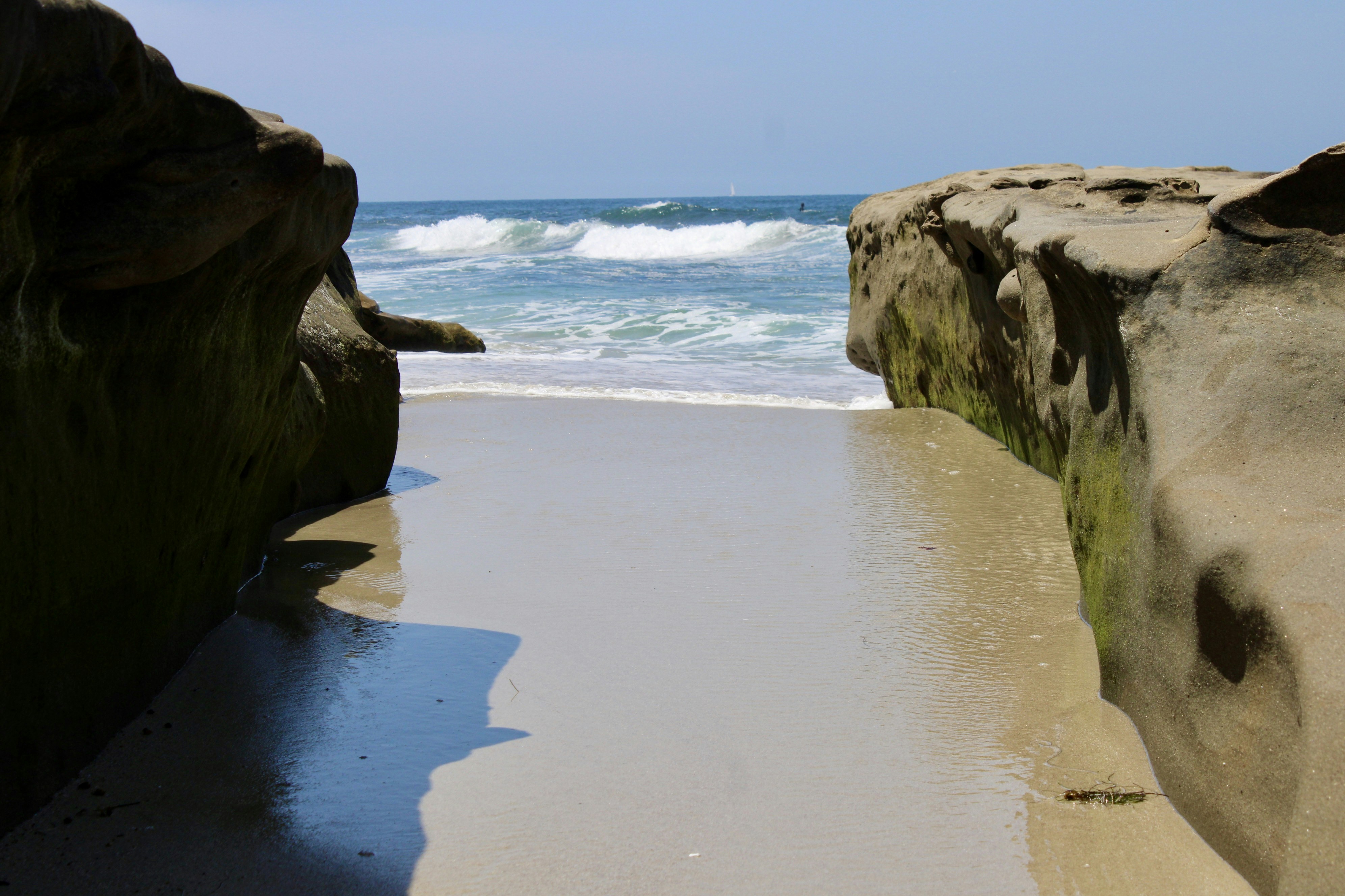 Sandy beach between two large rocks with ocean waves. photo – Free ...