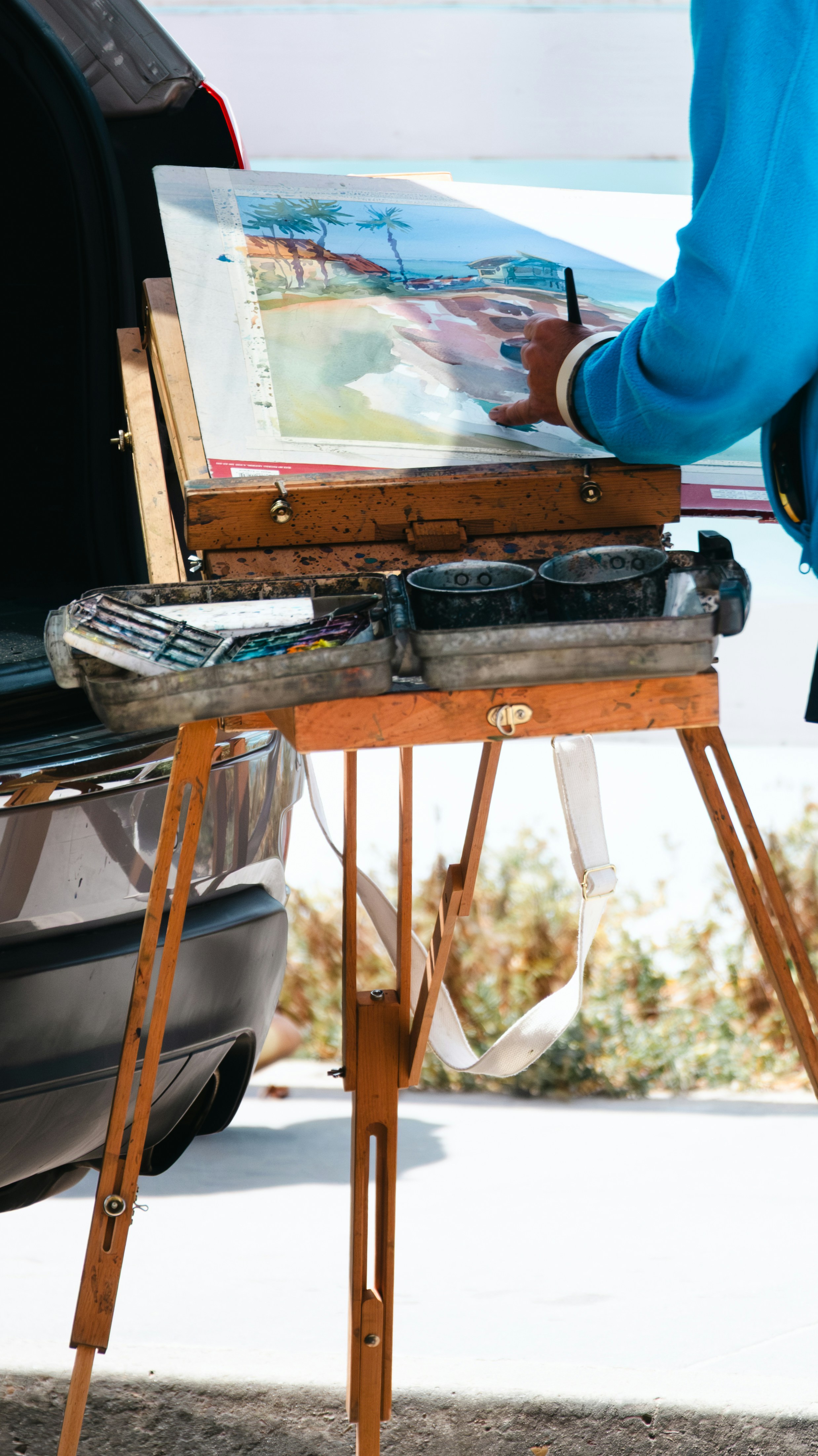 Artista pintando un paisaje de playa en un caballete al aire libre.