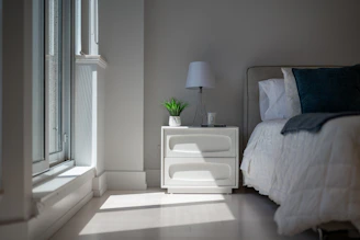 Sunlight illuminates a cozy bedroom with a bed and nightstand.