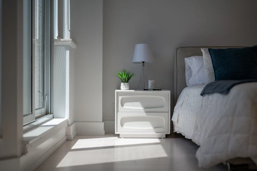 Sunlight illuminates a cozy bedroom with a bed and nightstand.
