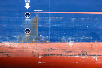 Weathered blue and red ship hull with markings and rust.