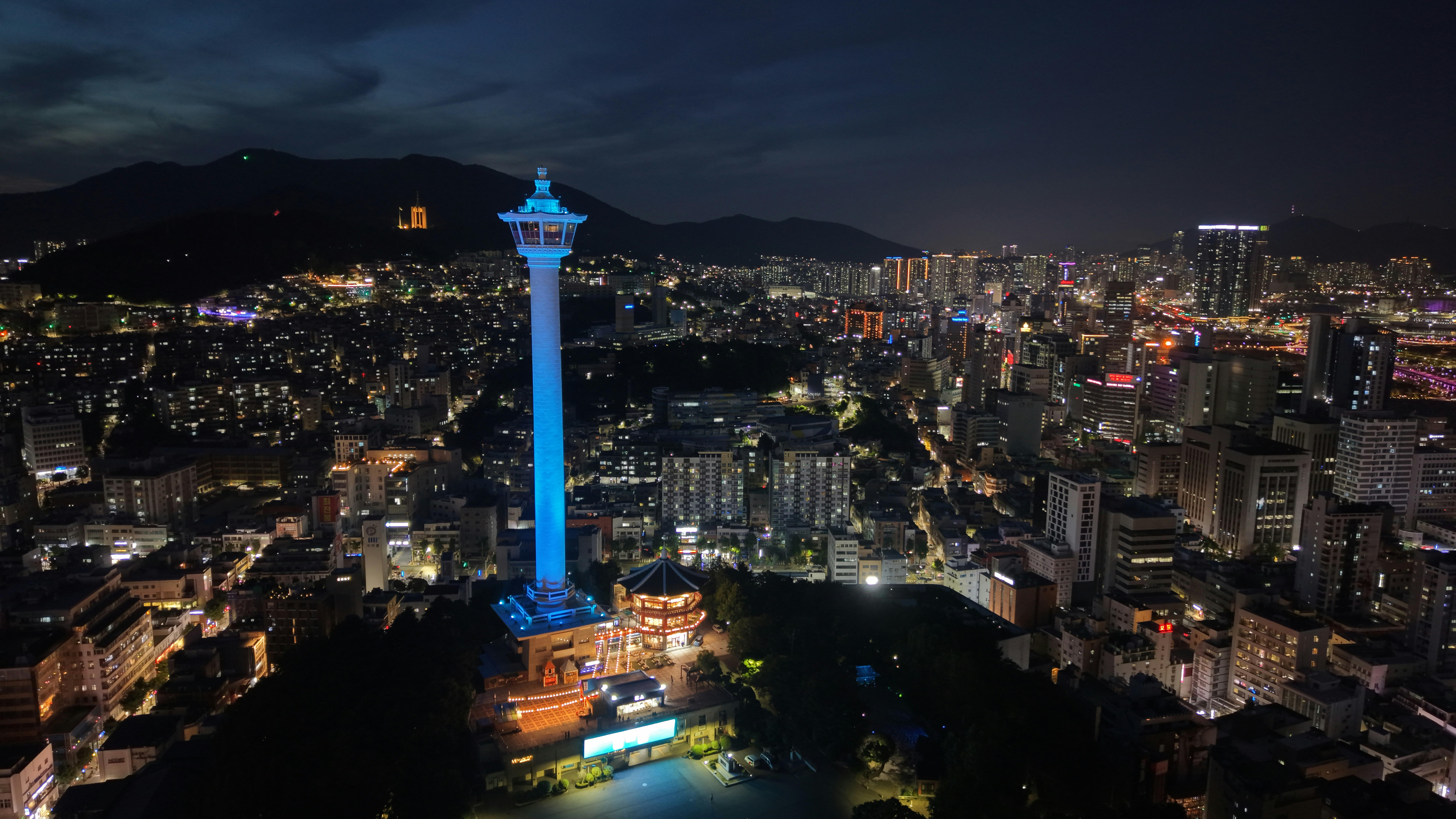 Night view of a city with a glowing blue tower.