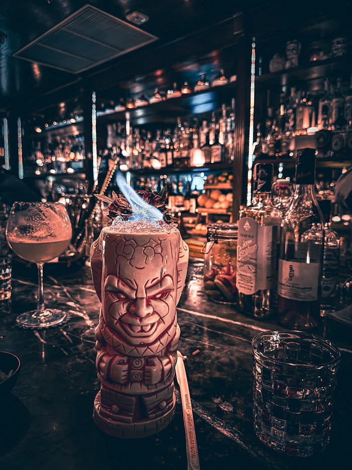 Flaming tiki cocktail on a dark bar counter