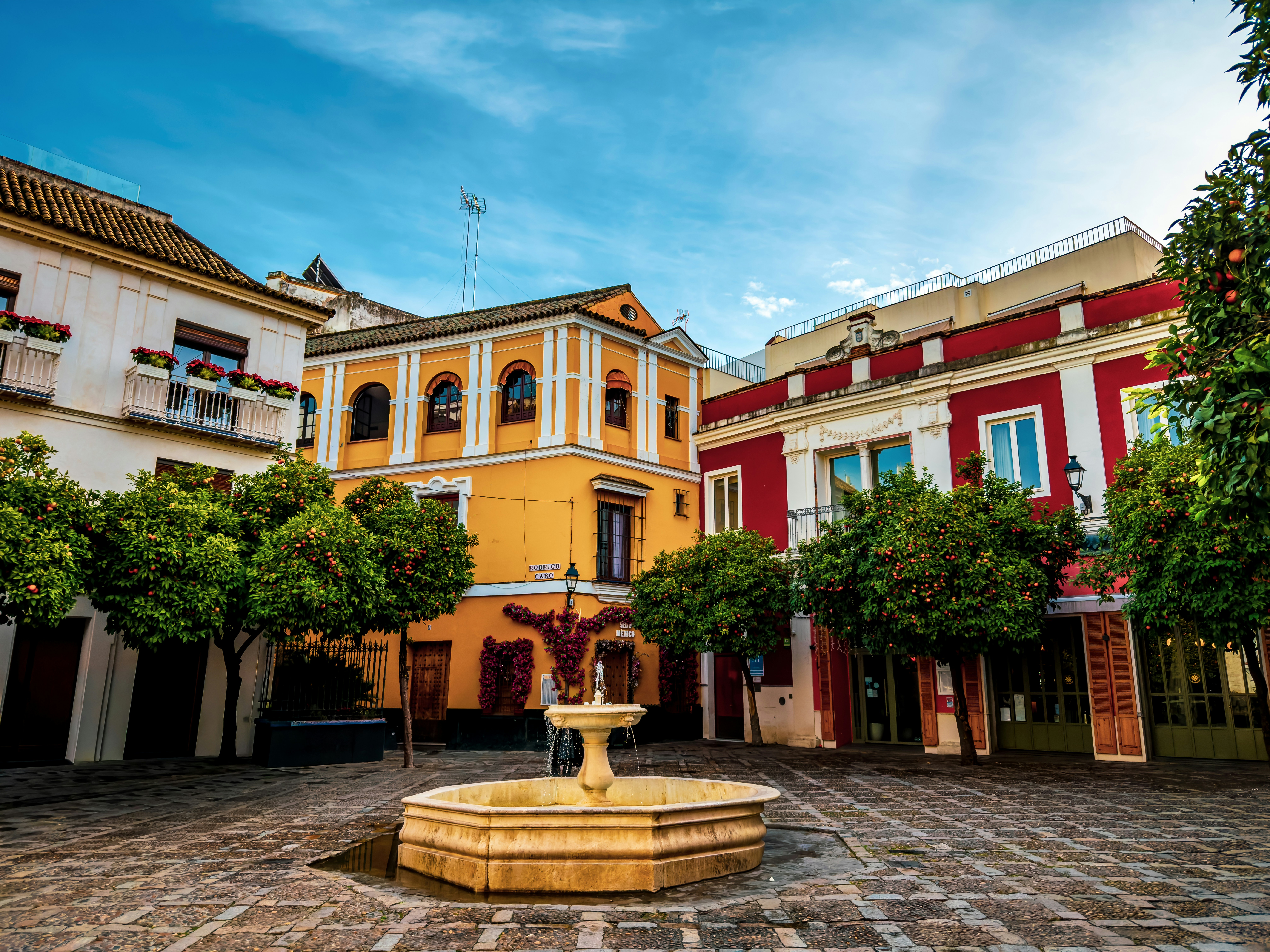 A small square with a fountain and orange trees in Seville's old town